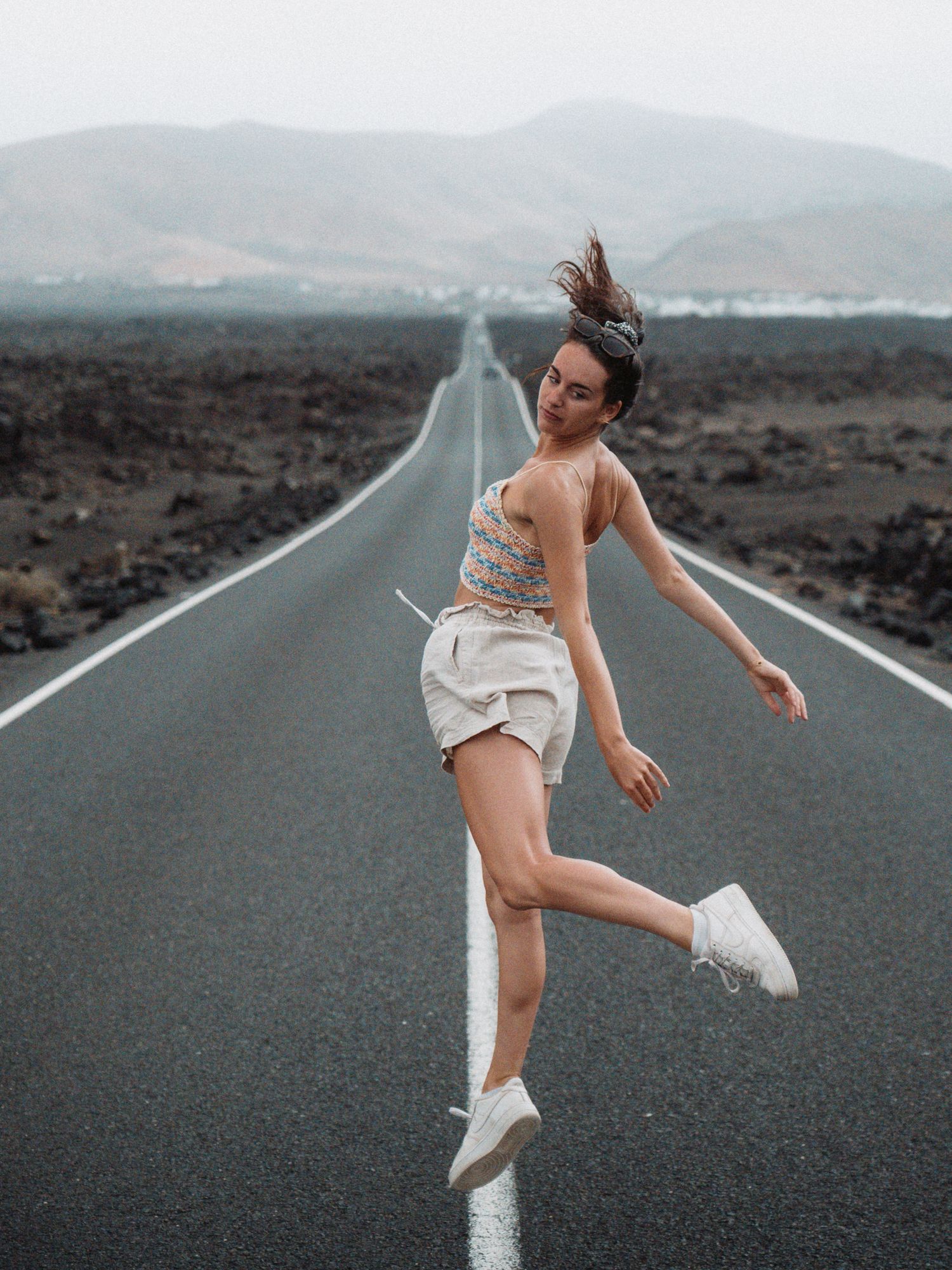Danseuse en pointe sur une route désertique, contraste saisissant entre grâce et environnement aride.