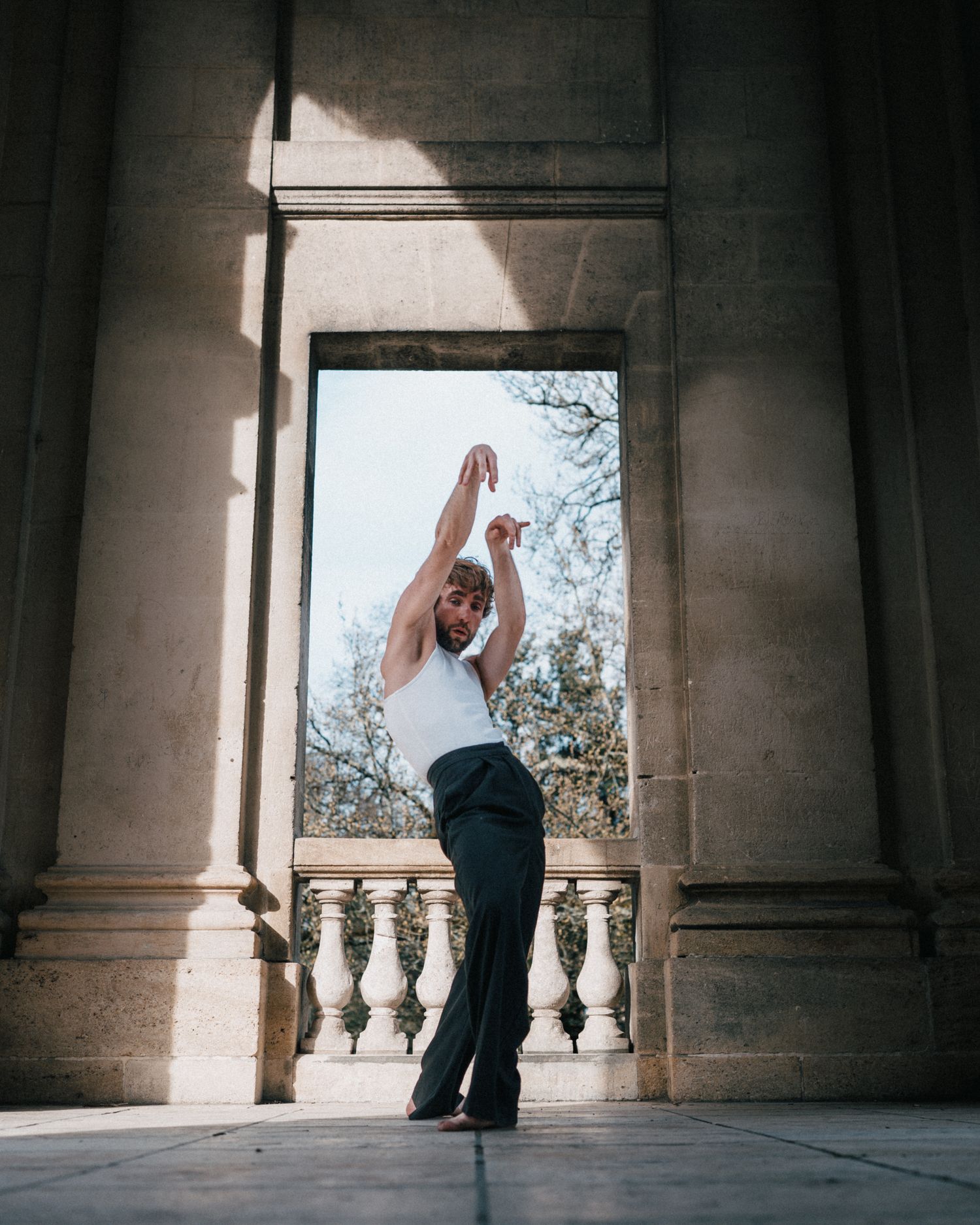 Photo chorégraphique dans un cadre architectural, lumière naturelle, pose expressive.