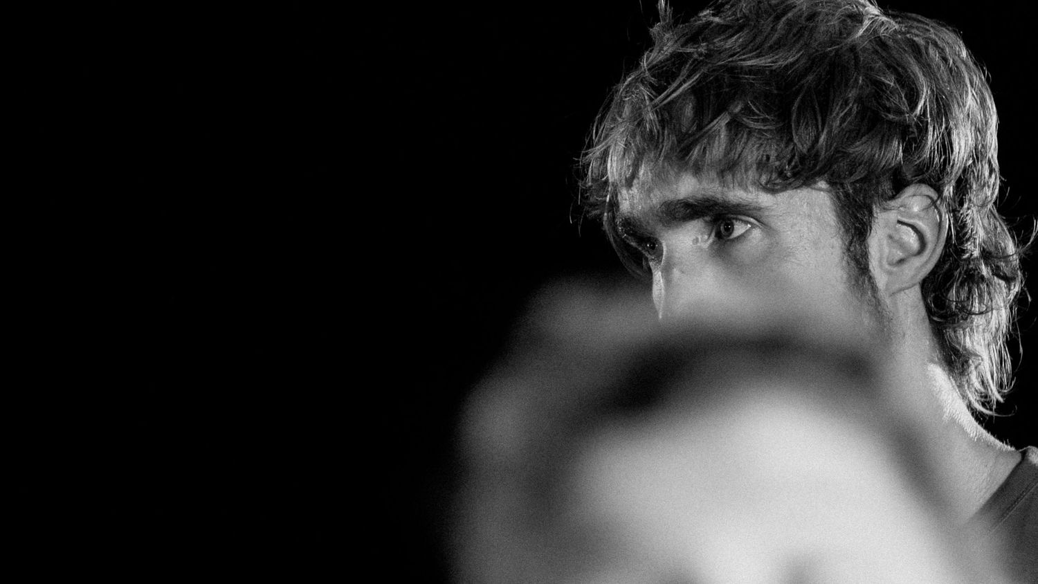 Portrait artistique noir et blanc d’un danseur homme, gros plan avec effet de flou artistique sur le visage, lumière contrastée – projet cho