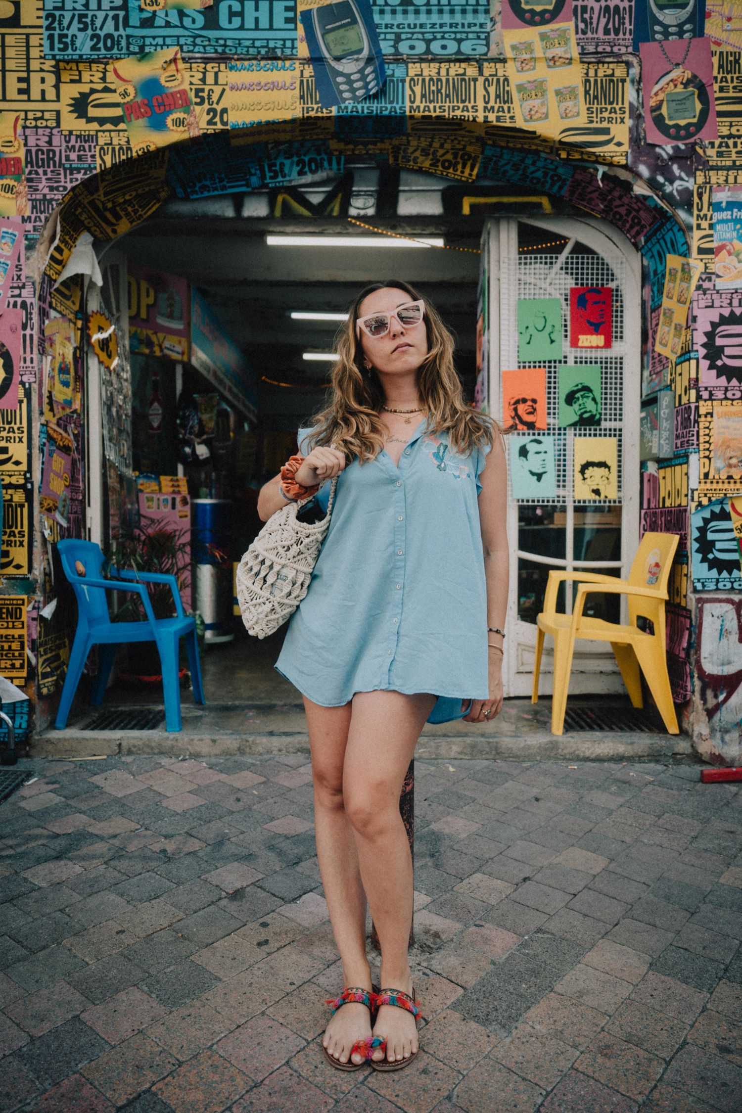 Portrait lifestyle urbain, robe d’été, ambiance colorée et artistique devant une boutique.