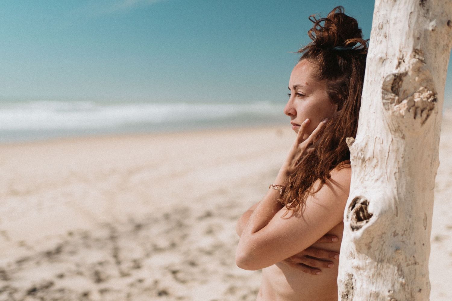 Portrait lifestyle d’une femme à la plage, lumière naturelle, ambiance estivale et poétique.