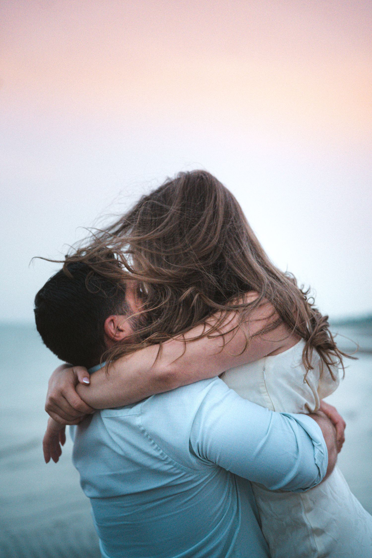 Romantic couple hugging and kissing during a golden hour engagement session in beach in Moncton, NB.