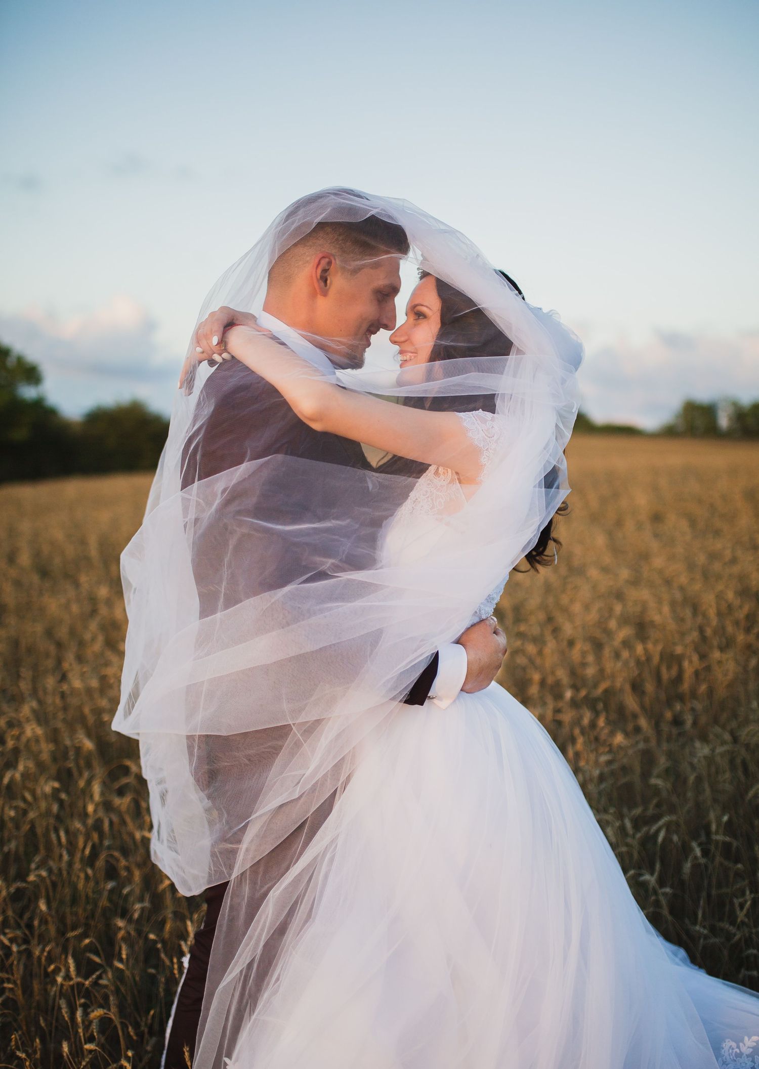 Couple in a field, engulfed in a veil