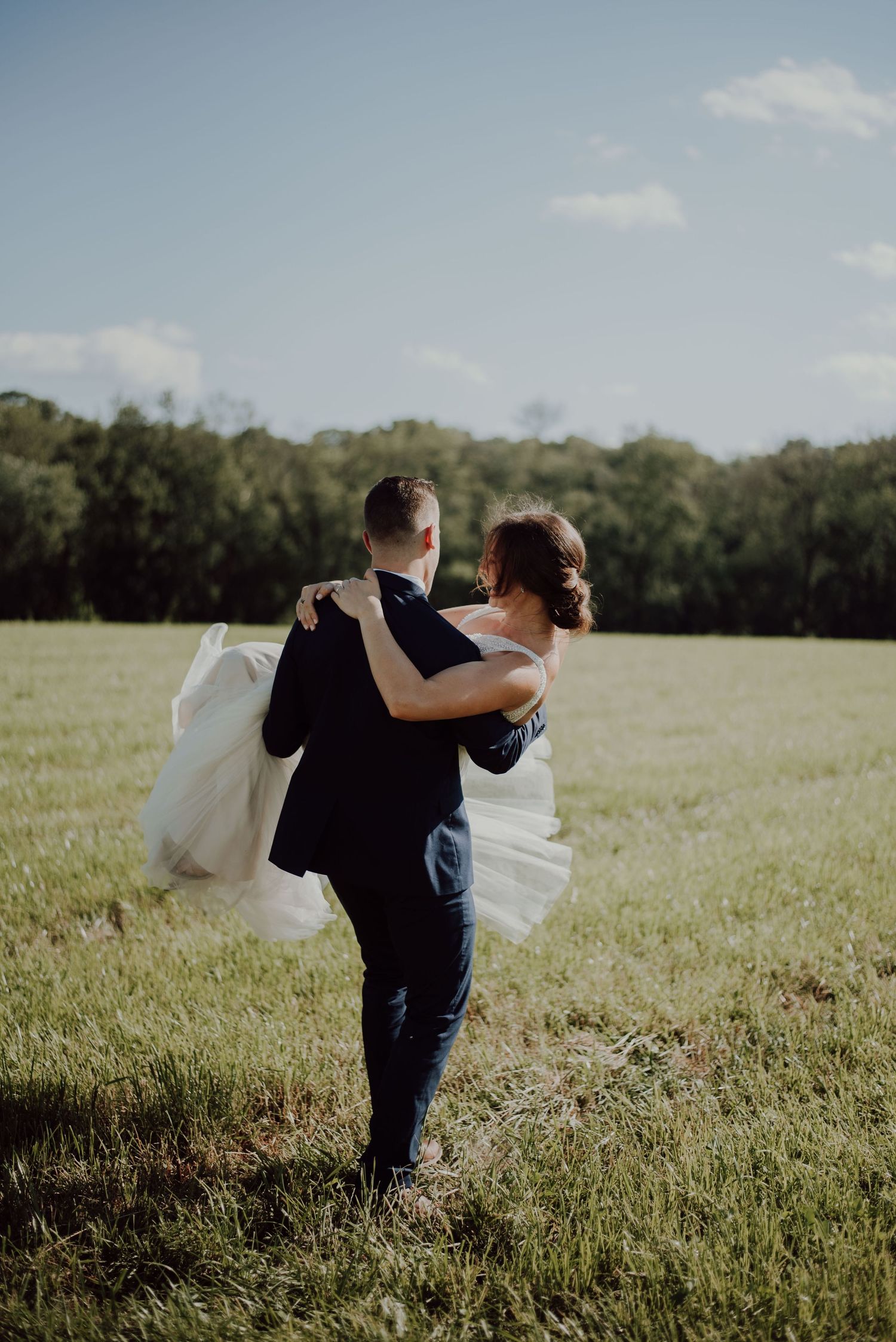 Husband lifting bride, walking across field