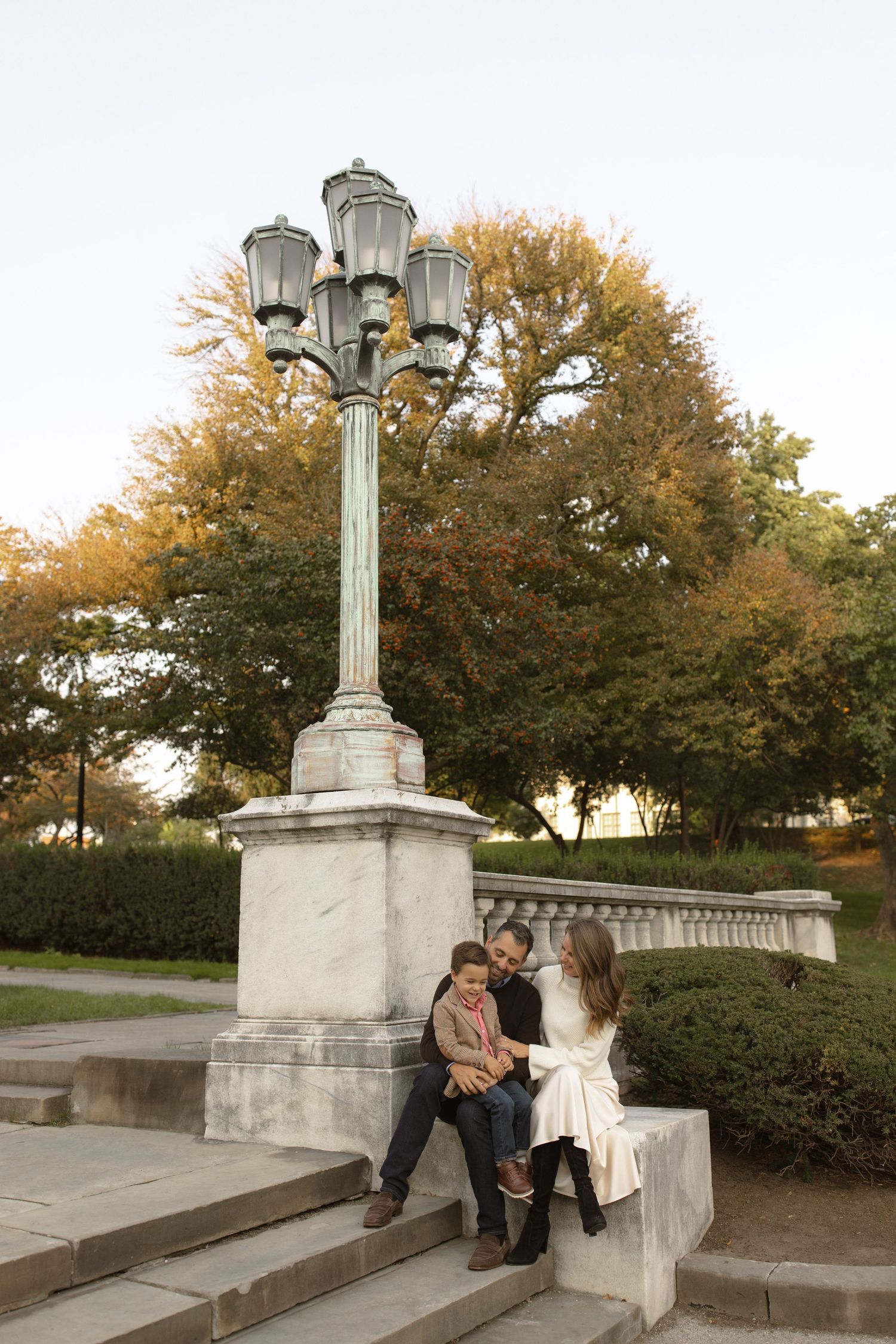 Beautiful ornate vintage lamp post stands tall amid autumn trees on stone steps in a park-like setting.