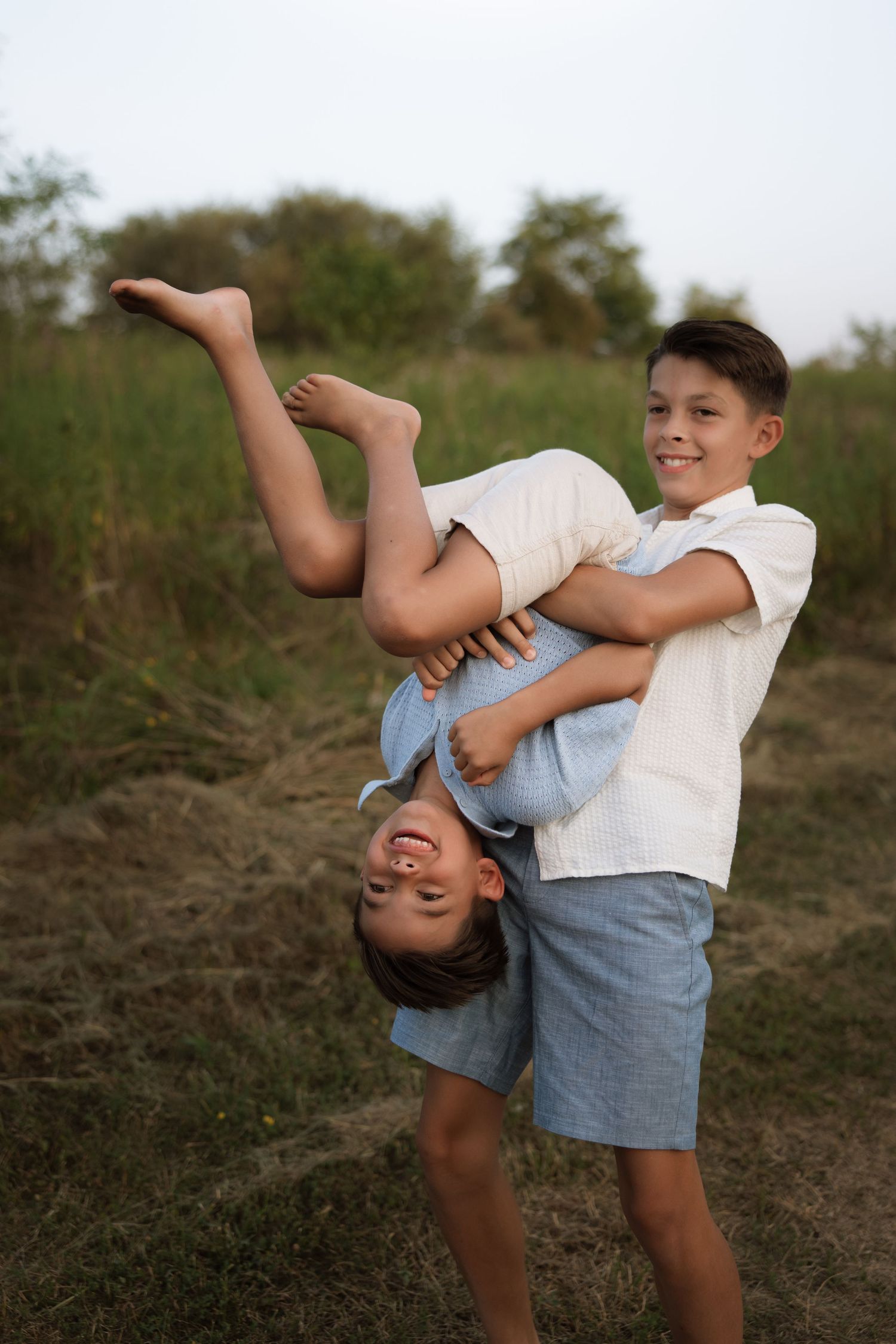 Two children playing and interacting playfully outdoors on a sunny day in casual summer clothes.