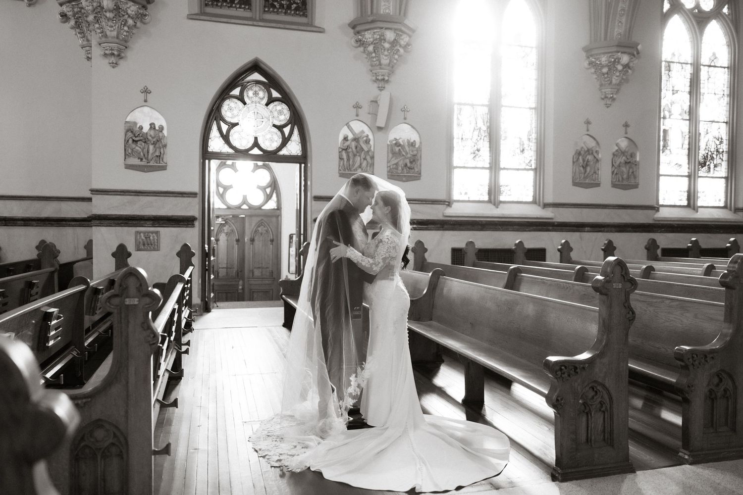 A romantic black and white wedding ceremony moment inside a historic church with Gothic architecture and wooden pews.