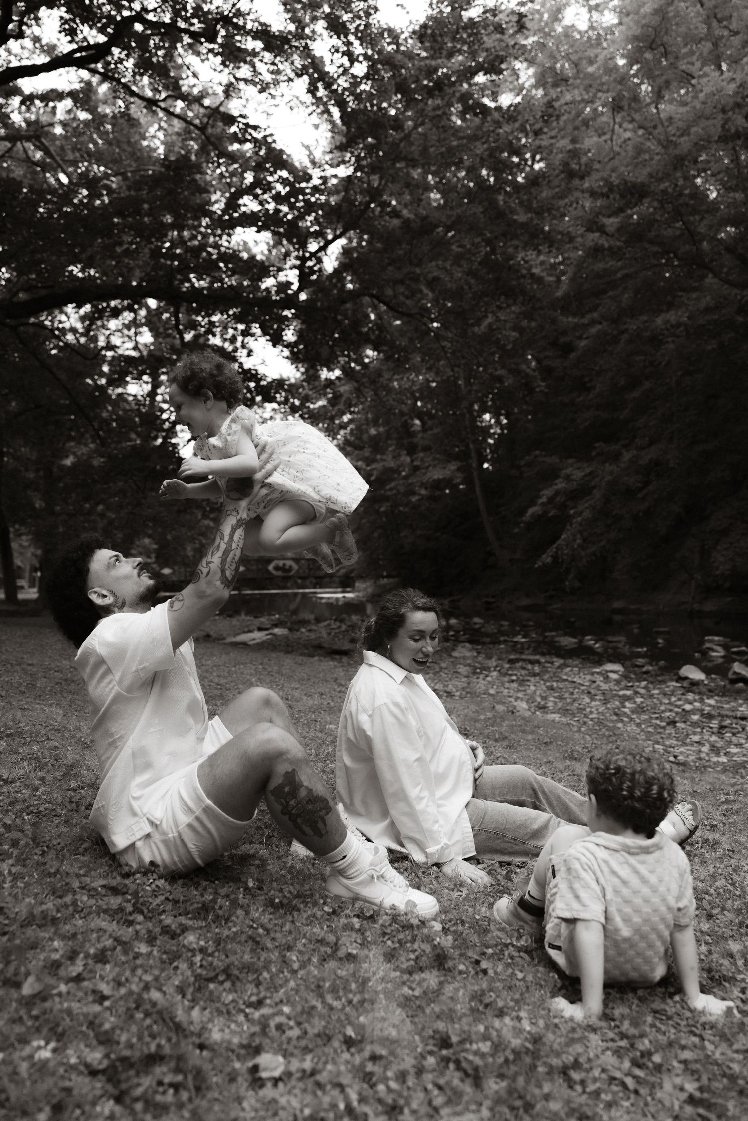 Playful group having fun together on grassy lawn in black and white photograph.