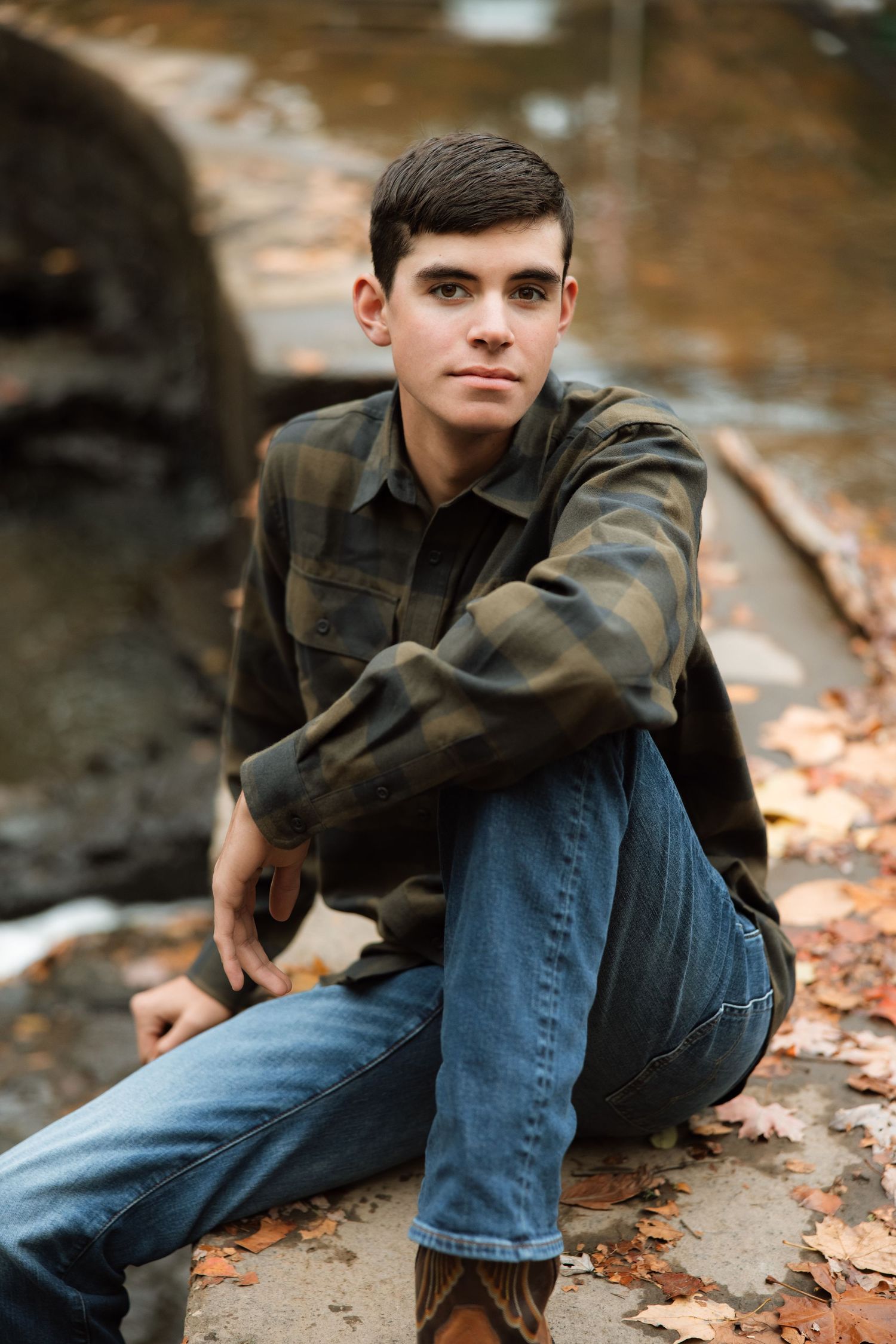 A person in dark clothing and jeans reclines on fallen autumn leaves in a series of outdoor portrait poses.
