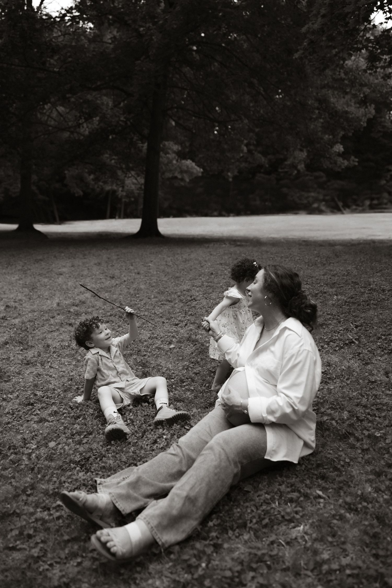 A black and white photo of joyful play time in a park with trees in the background.