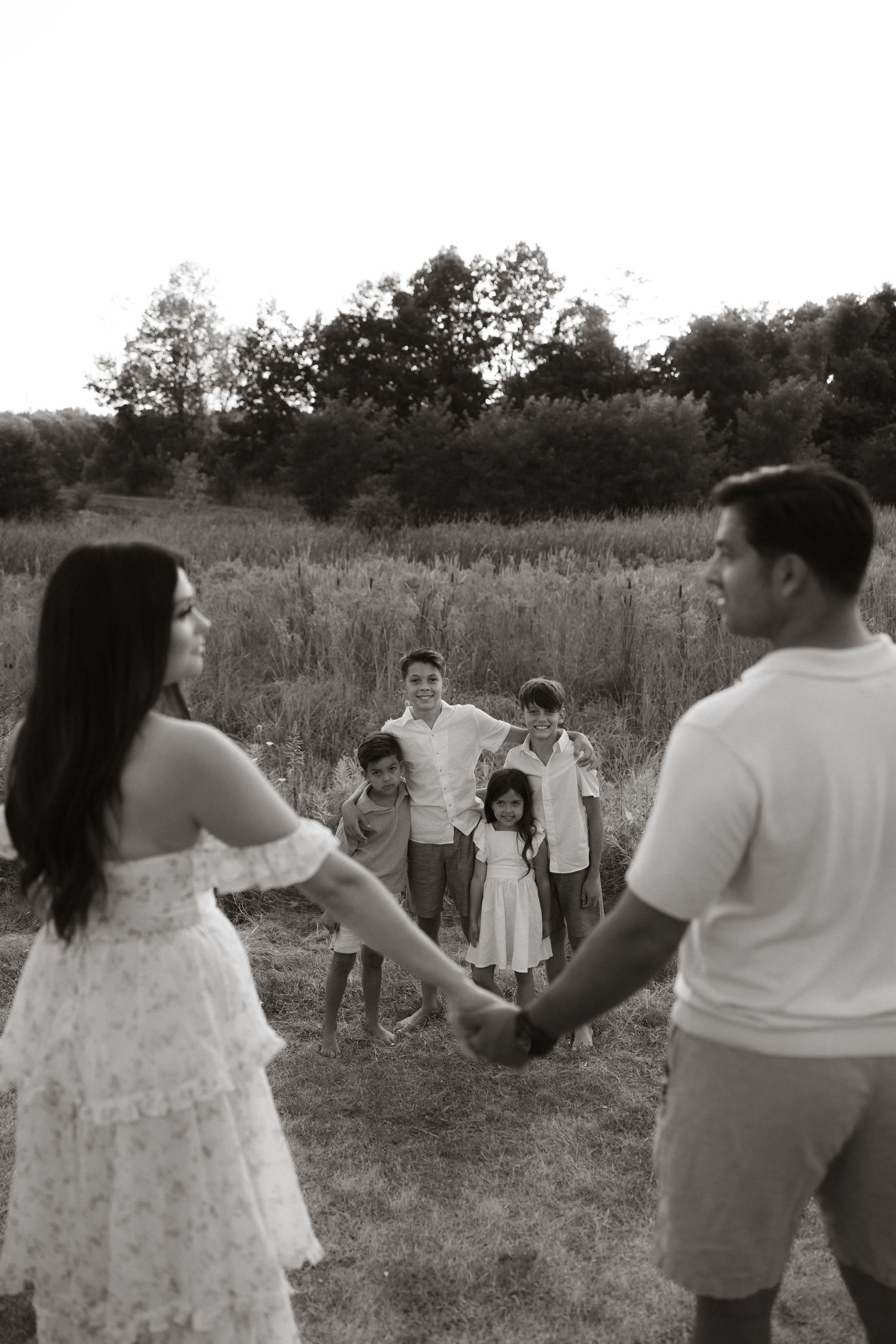 Family group poses playfully across a series of outdoor photographs in a golden field with natural lighting.