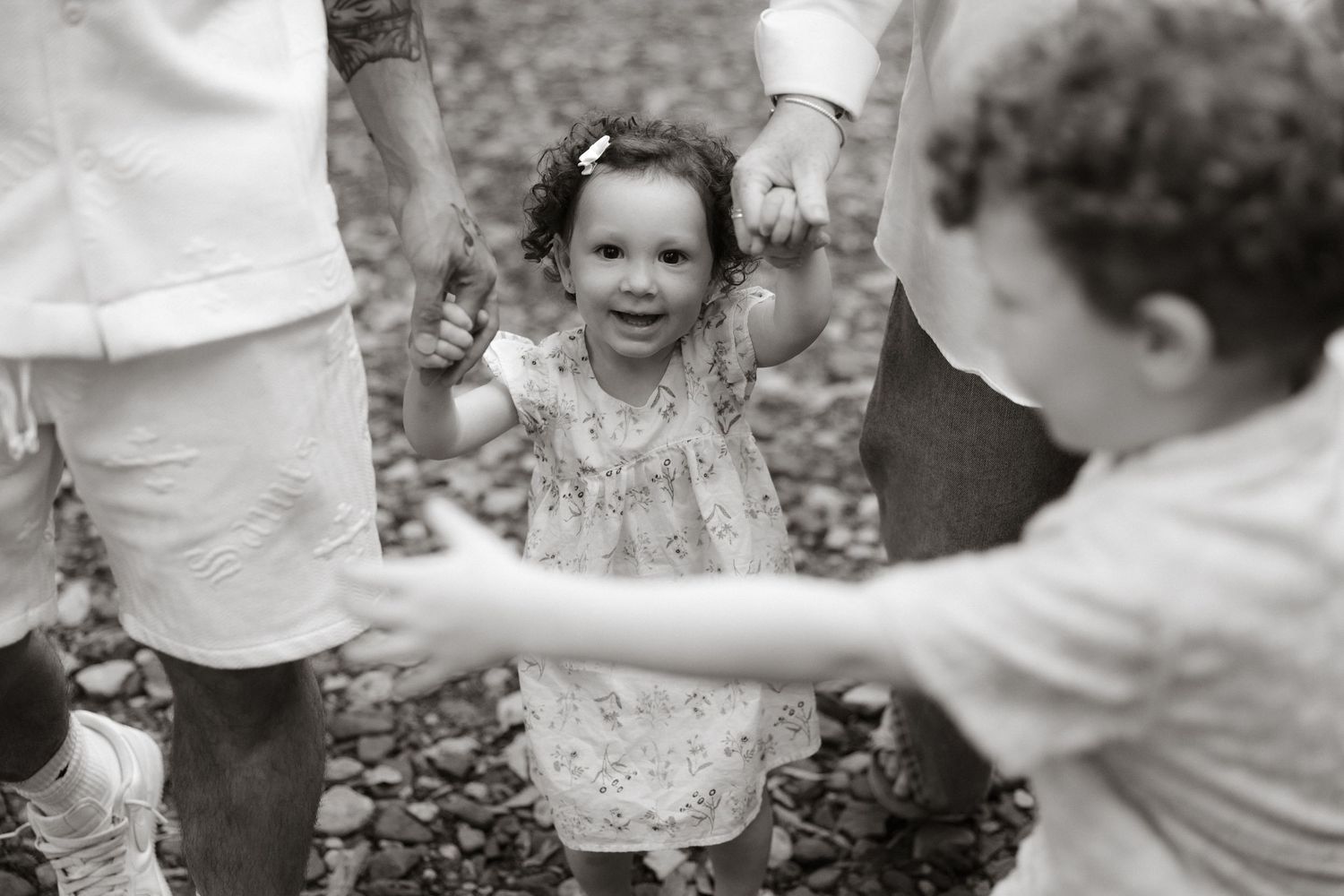 Children playing together outdoors while exploring and collecting small items in a natural setting during a summer day.