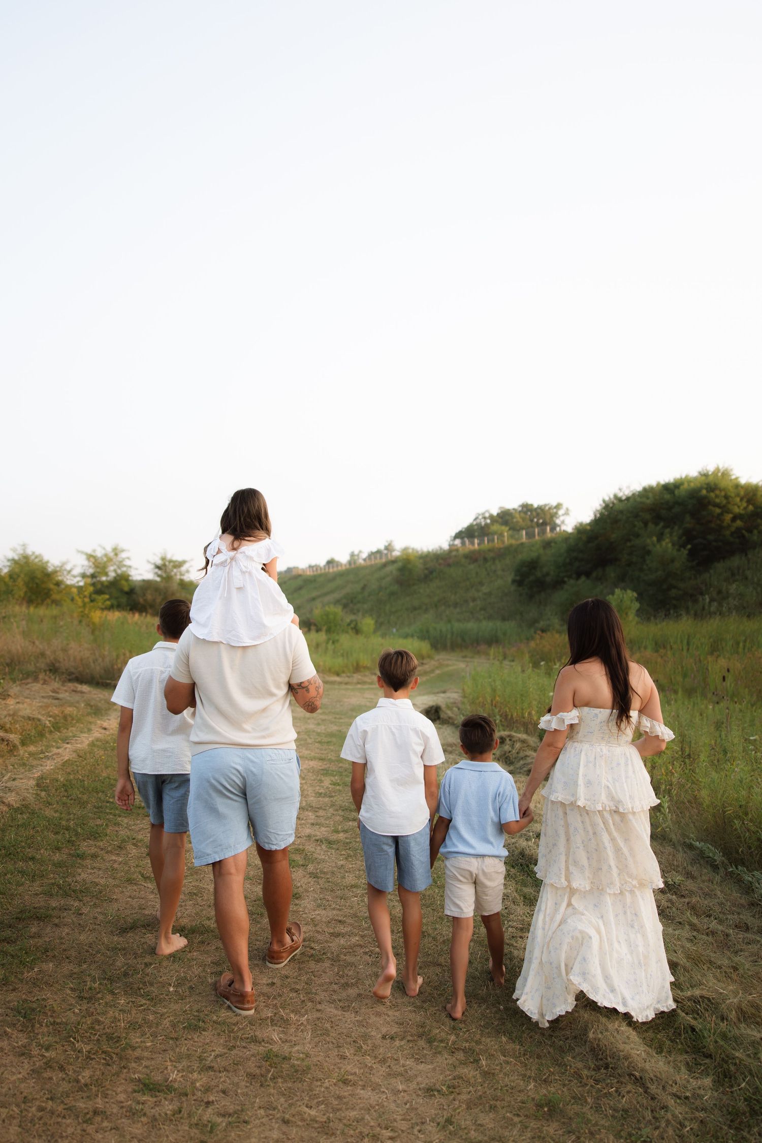 People walking together down a grassy path in coordinated blue and white outfits, viewed from behind.
