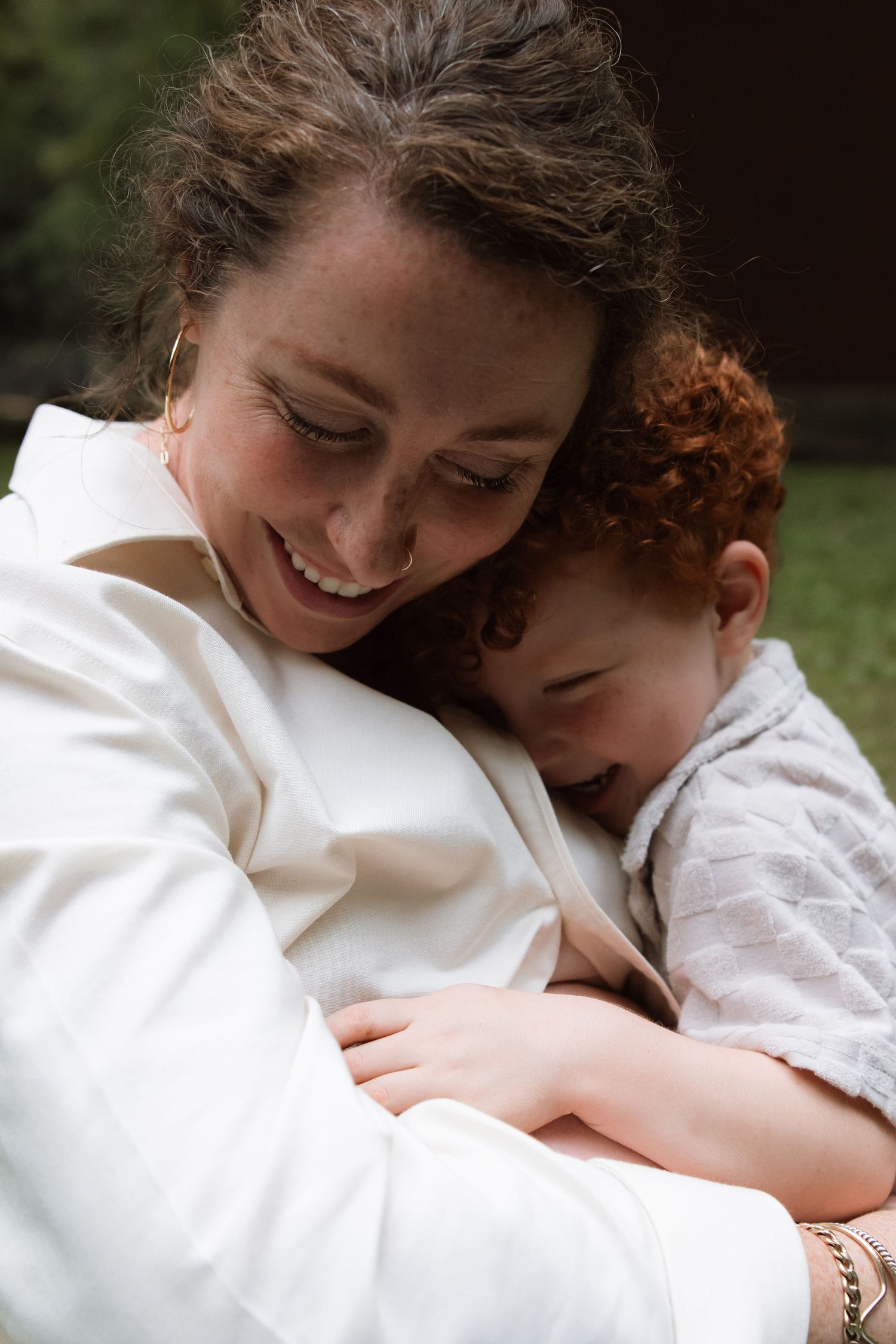 A tender moment captured showing a close embrace and joyful laughter against a natural outdoor background.