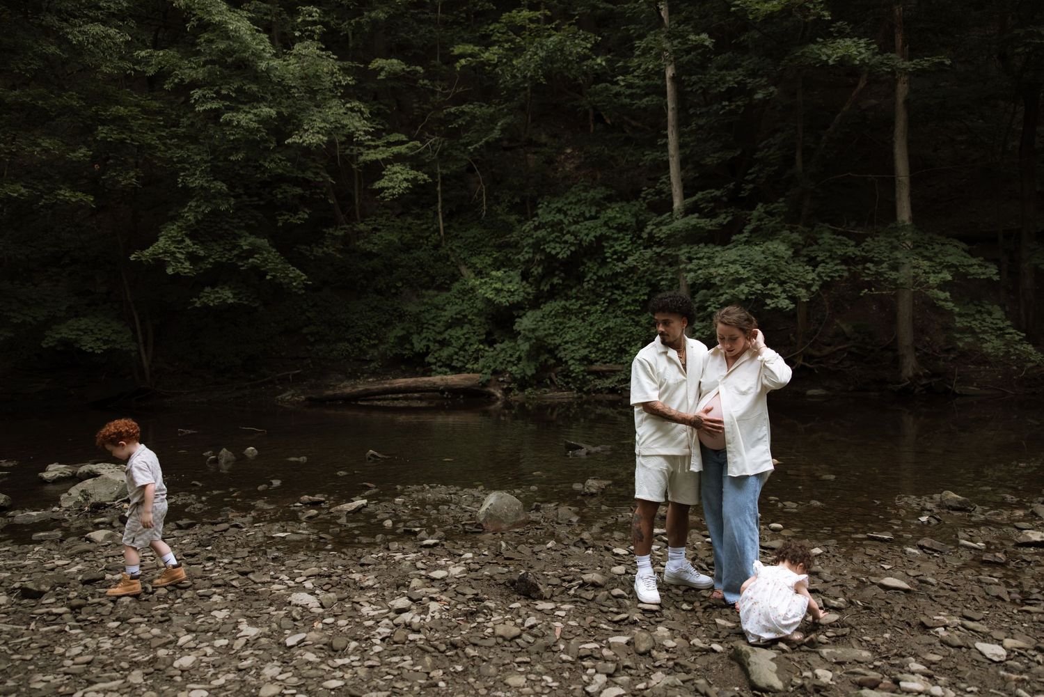 A couple holds a ceremony in a tranquil forest setting surrounded by tall trees and natural light.