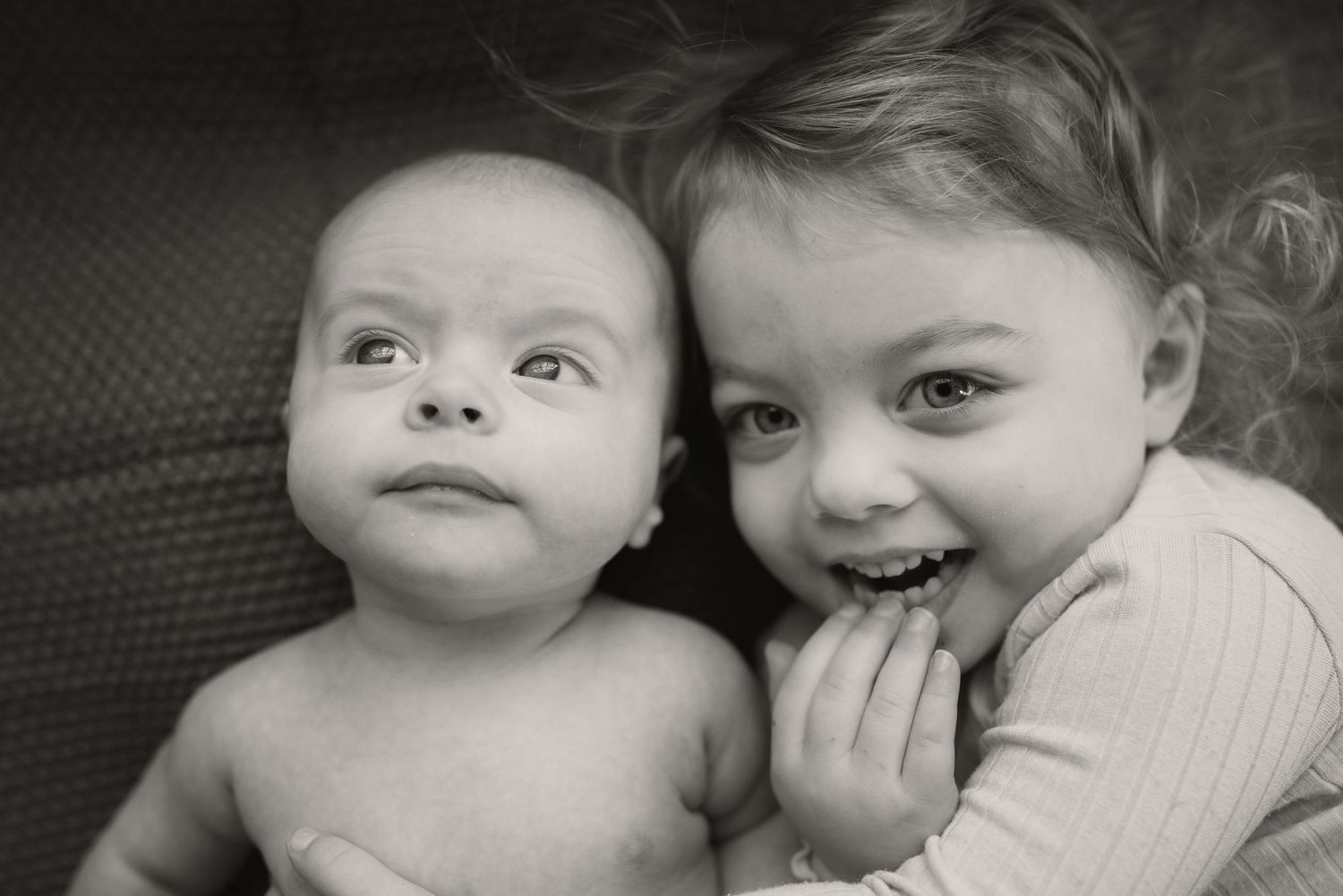Two young children sharing a sweet moment together on dark furniture.