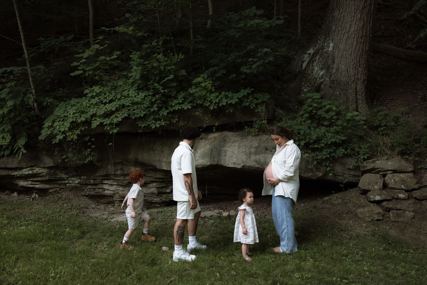 Group wearing white protective gear searches for wild mushrooms in a lush forest setting.