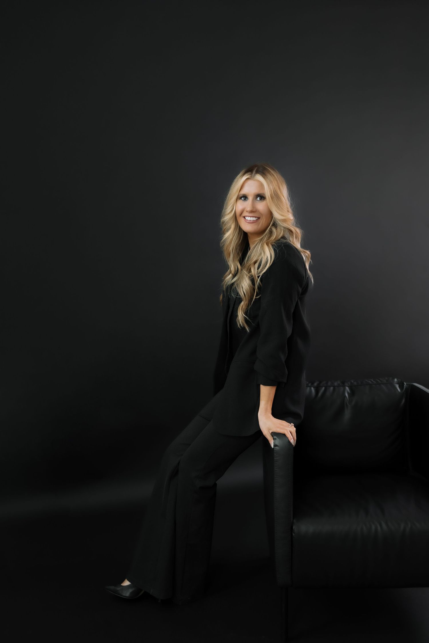 Professional studio portraits showing elegant blonde woman in black outfit posing against dark background.