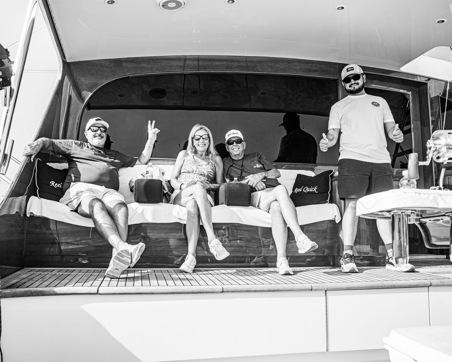 Group of friends relaxing on a luxury yacht deck, posing and smiling in black and white photo.