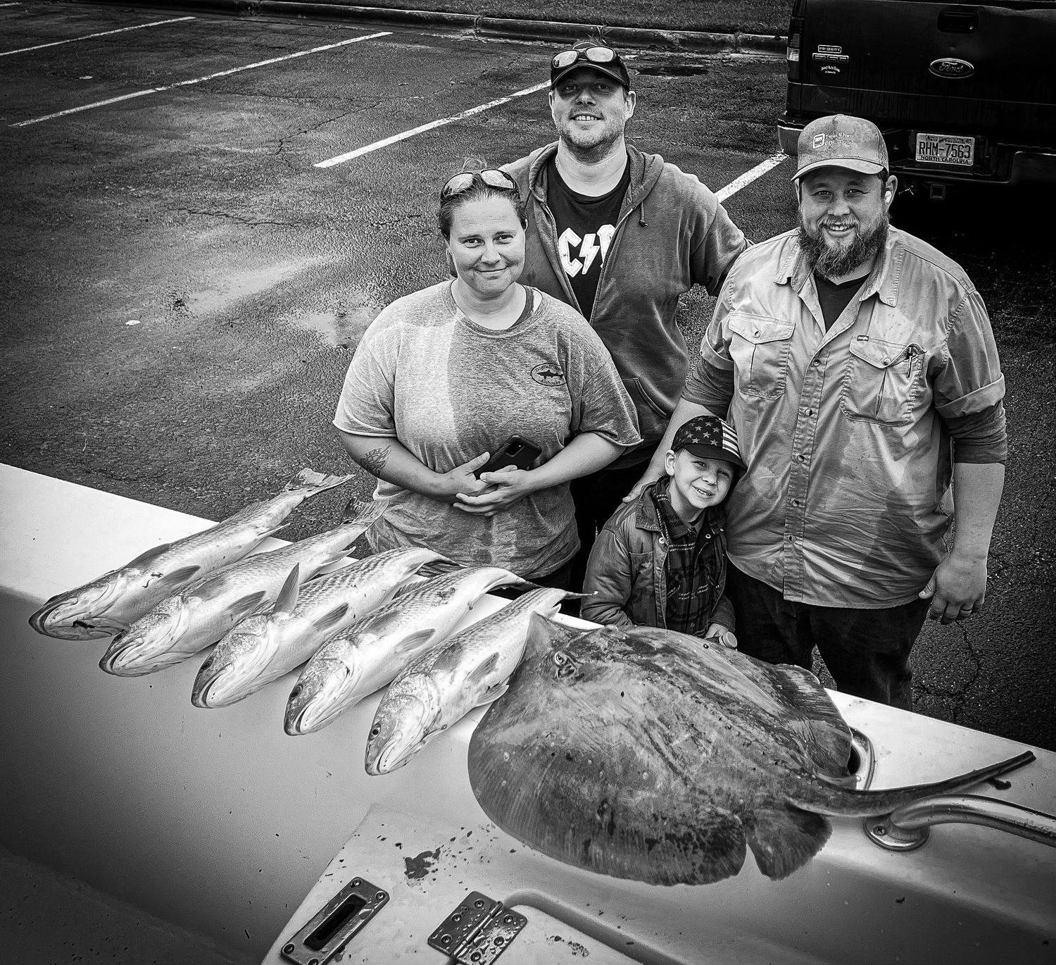 Group of anglers displaying their impressive catch of fish including several redfish on a boat deck.