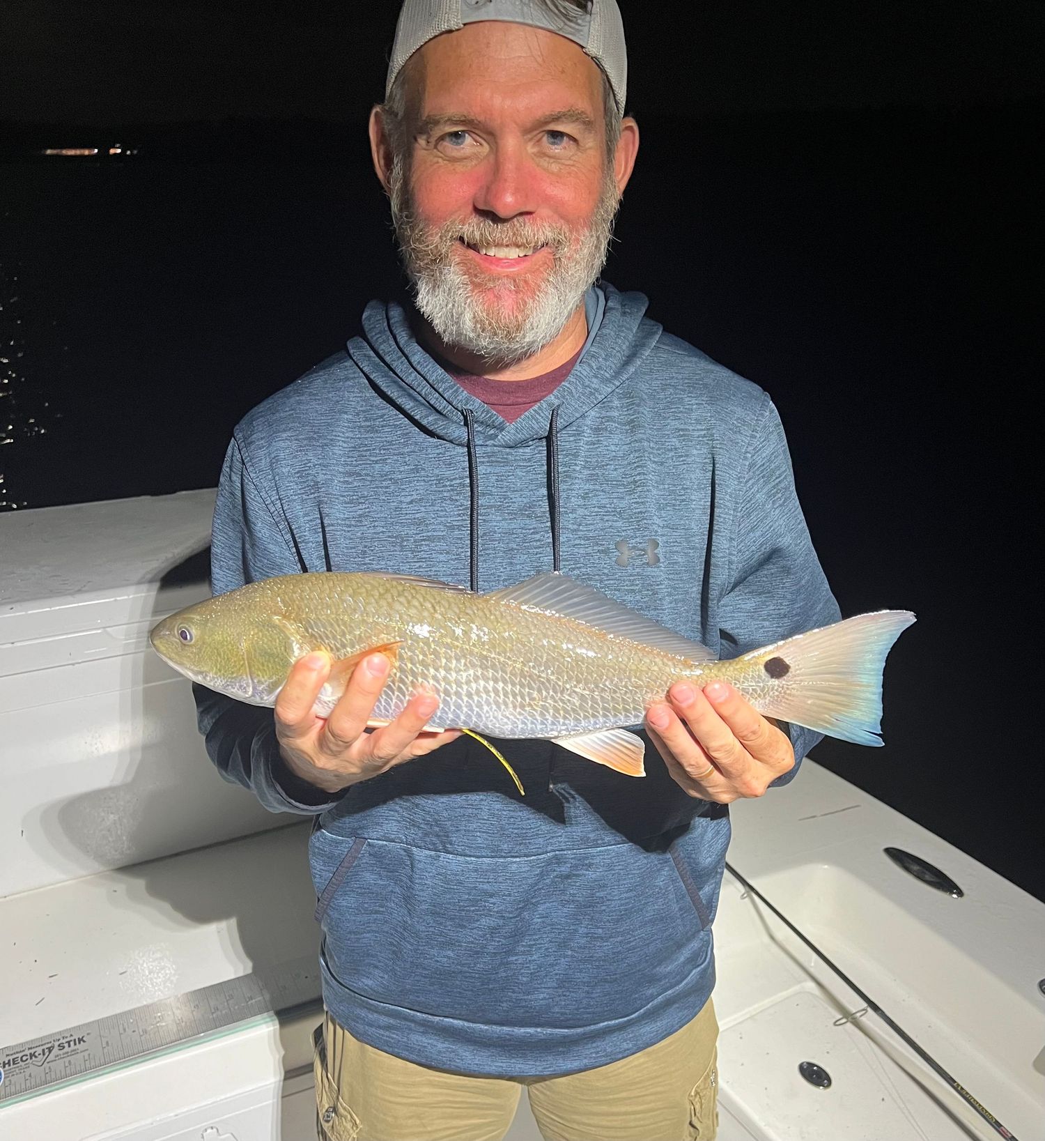 Beautiful redfish displayed during nighttime fishing expedition on white boat.