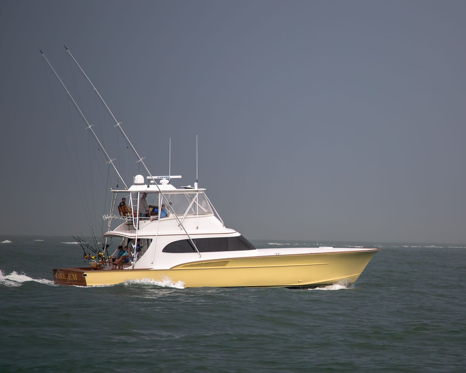Large yellow and white sportfishing yacht navigating through choppy waters with fishing equipment deployed.