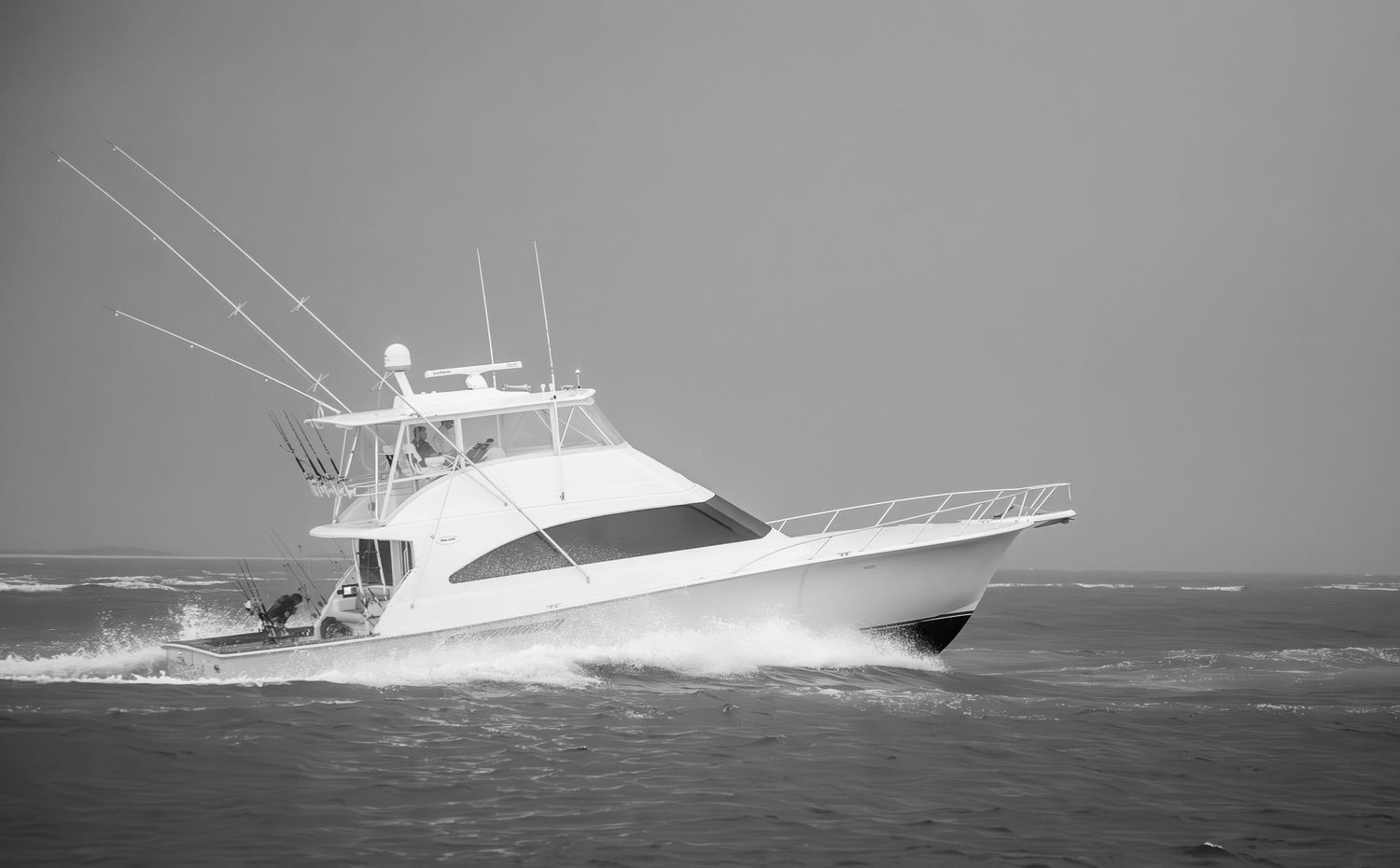 Sport fishing vessel cutting through rough seas in black and white photography.