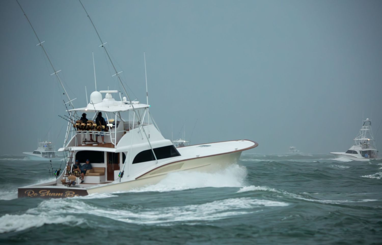 Luxury sport fishing yacht powering through rough seas with waves splashing against hull.