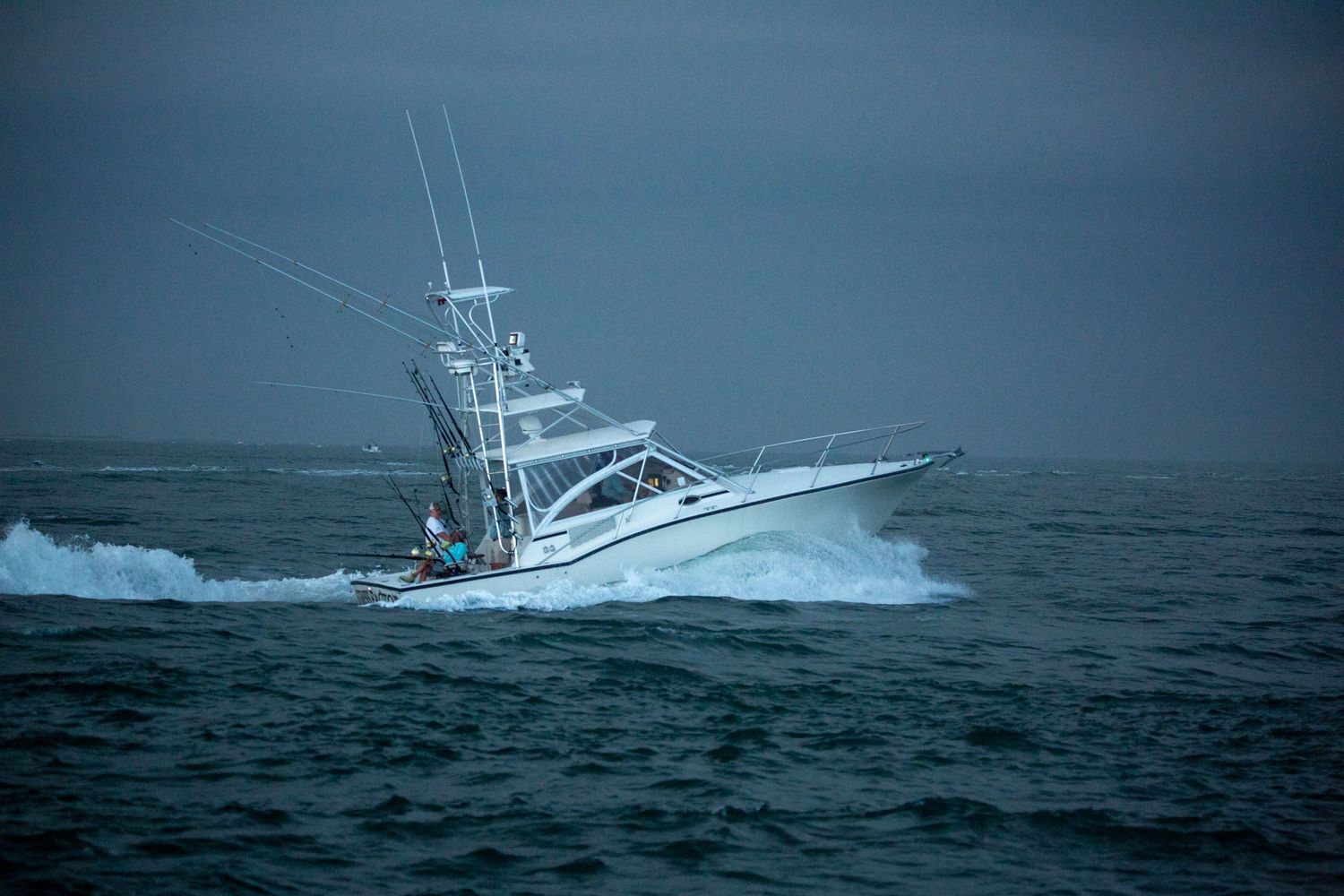 Sport fishing vessel battling through stormy seas with heavy waves.