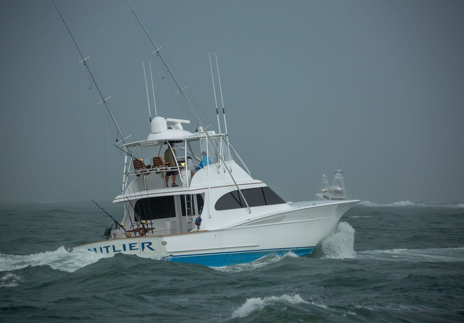 White sport fishing vessels crashing through heavy seas on a stormy day.