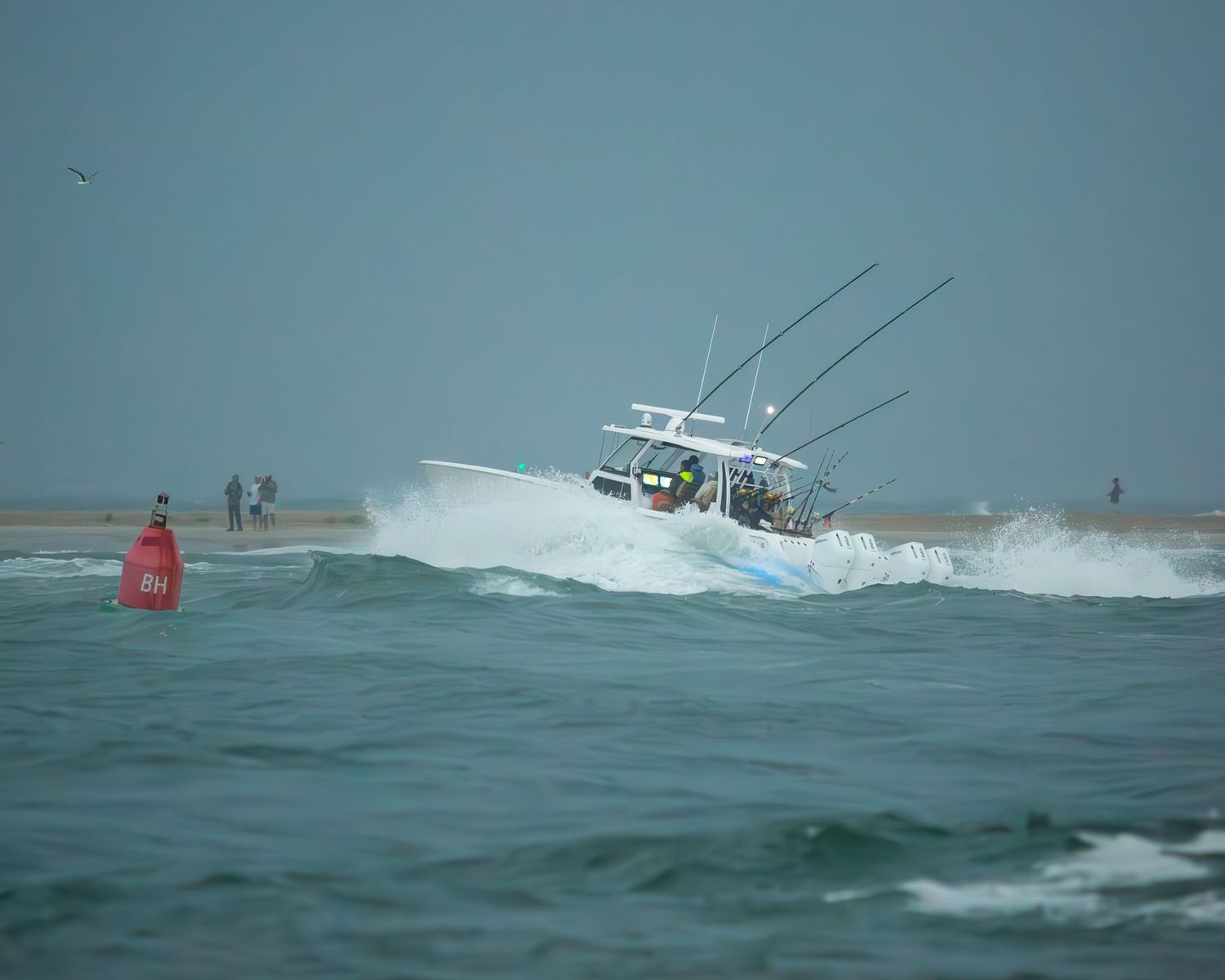 Center console boat navigates rough seas near coastal beach with buoy.