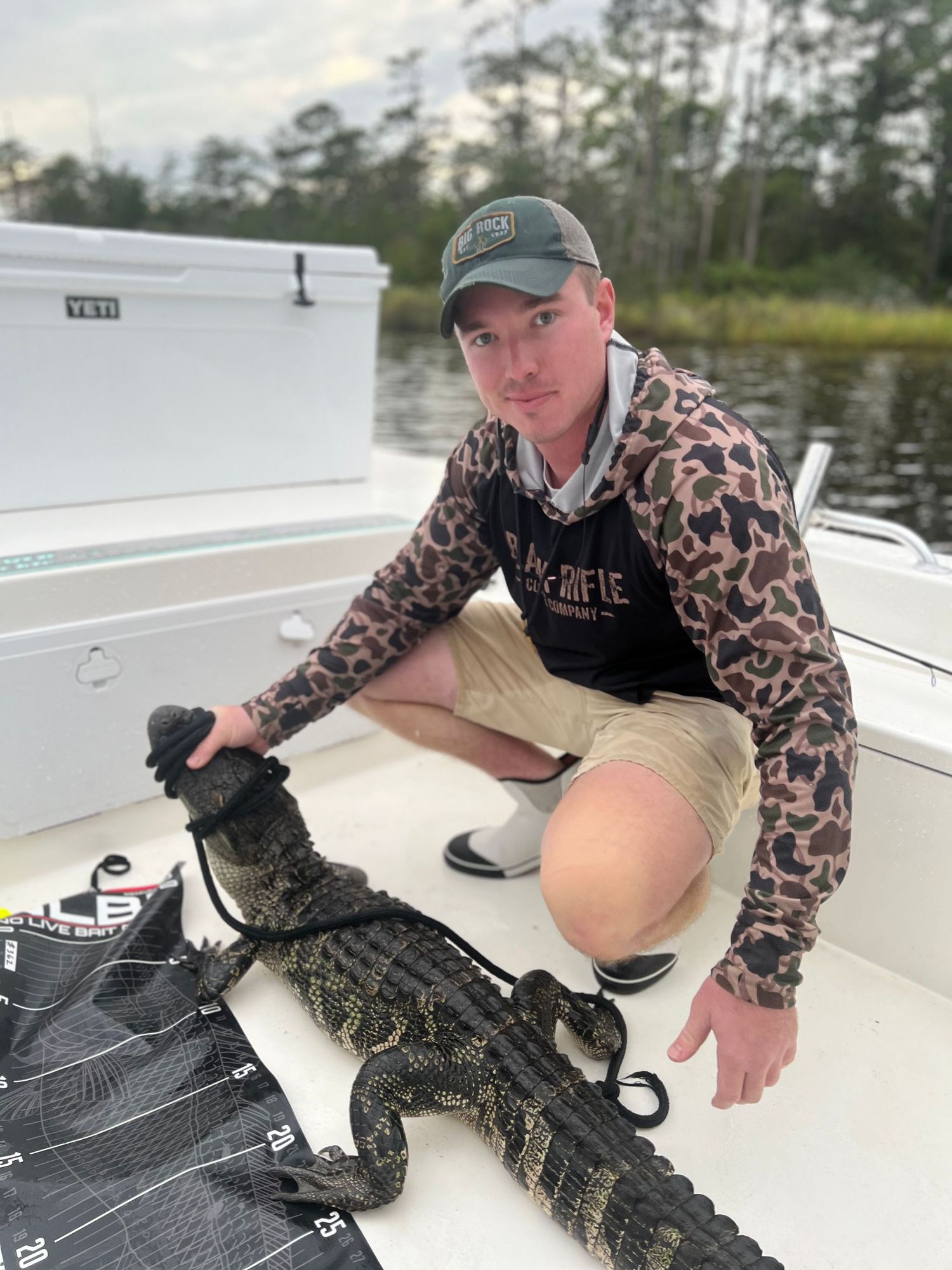 Large alligator caught and secured on boat deck during marsh fishing trip.