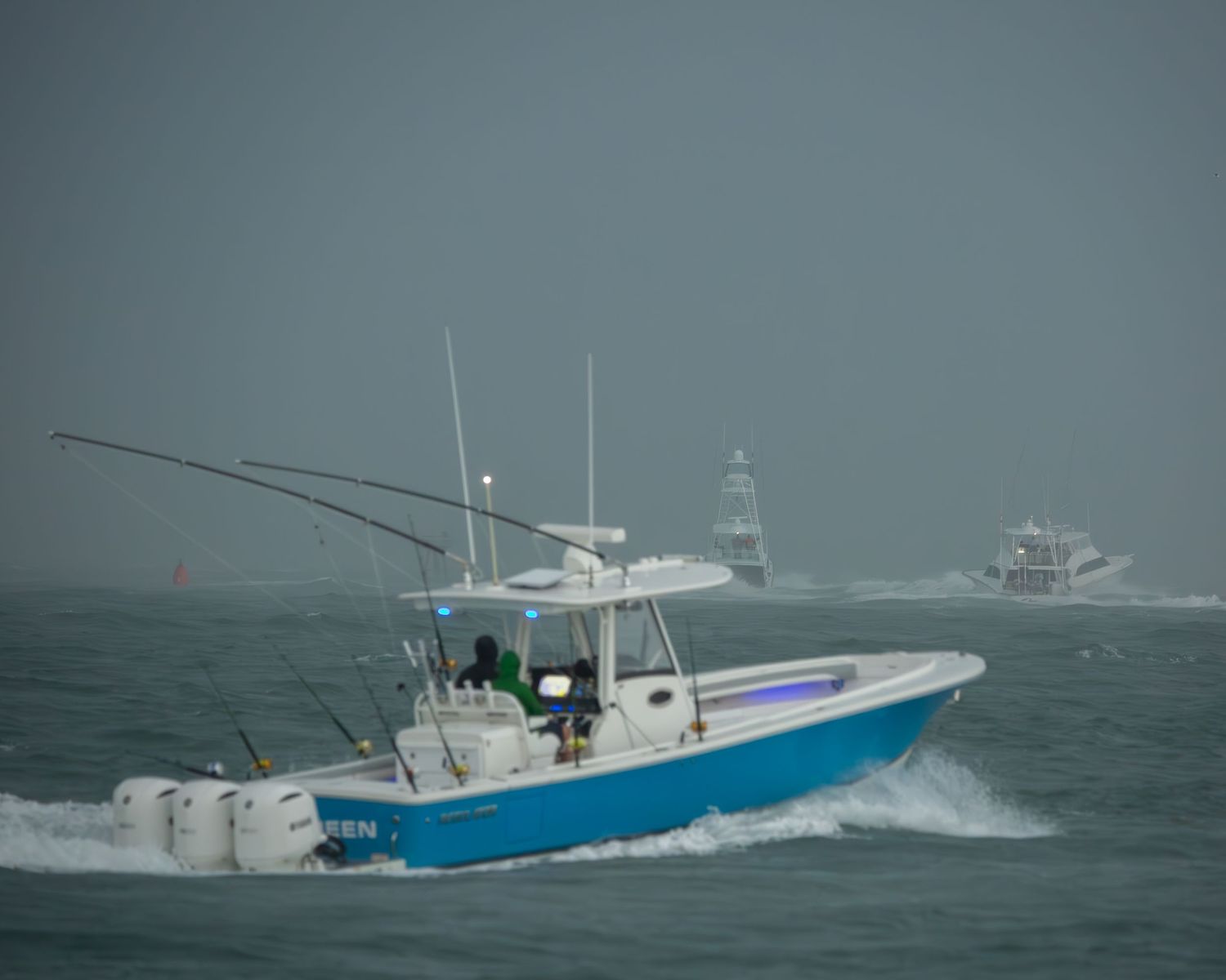 Charter fishing boat with outriggers navigates through choppy seas near other vessels.