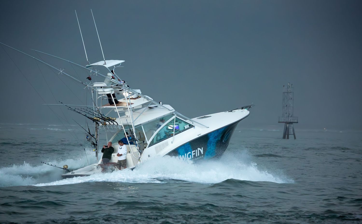 Sport fishing boat plows through heavy seas with water spraying from bow.