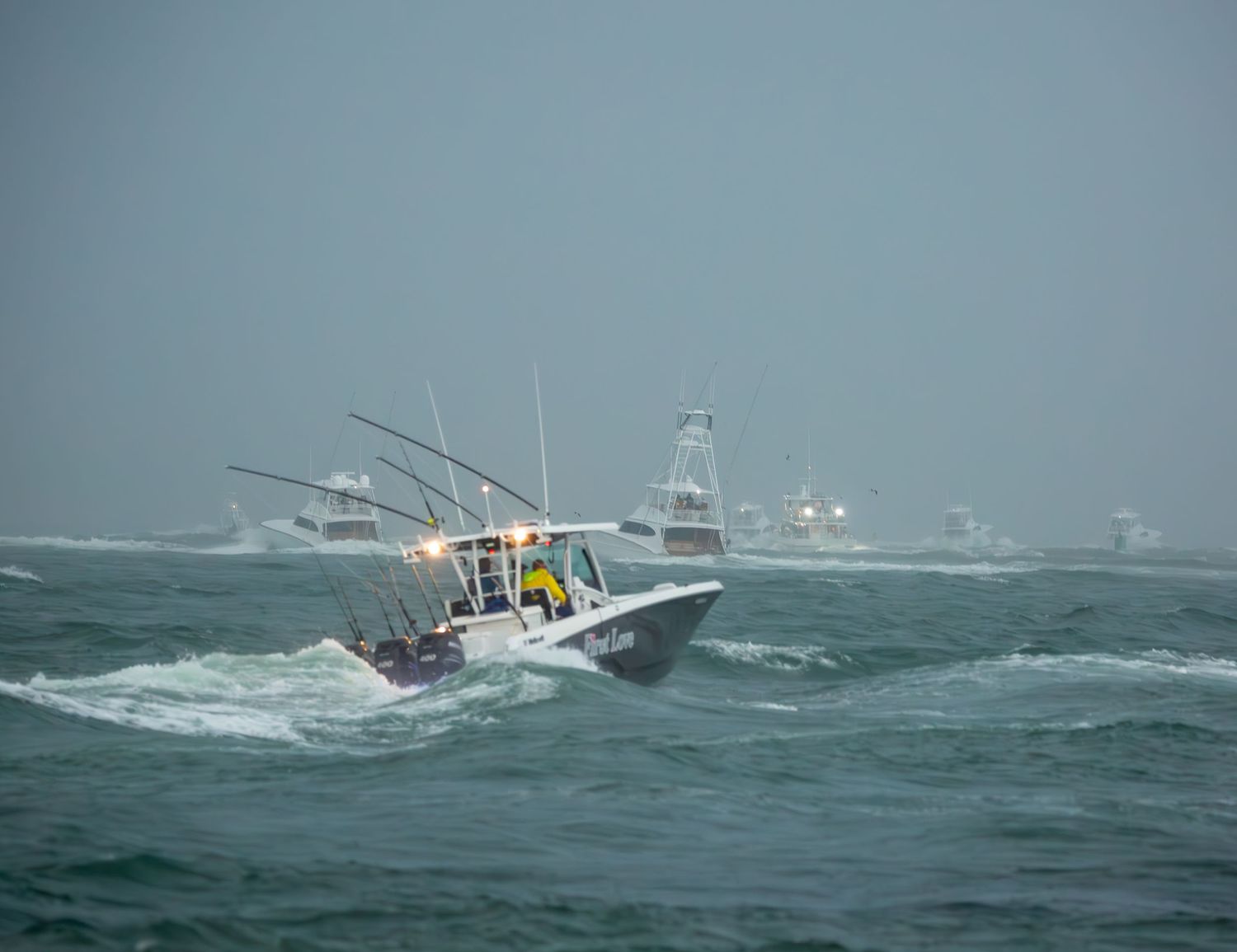 Sport fishing vessels braving rough ocean conditions in foggy weather.