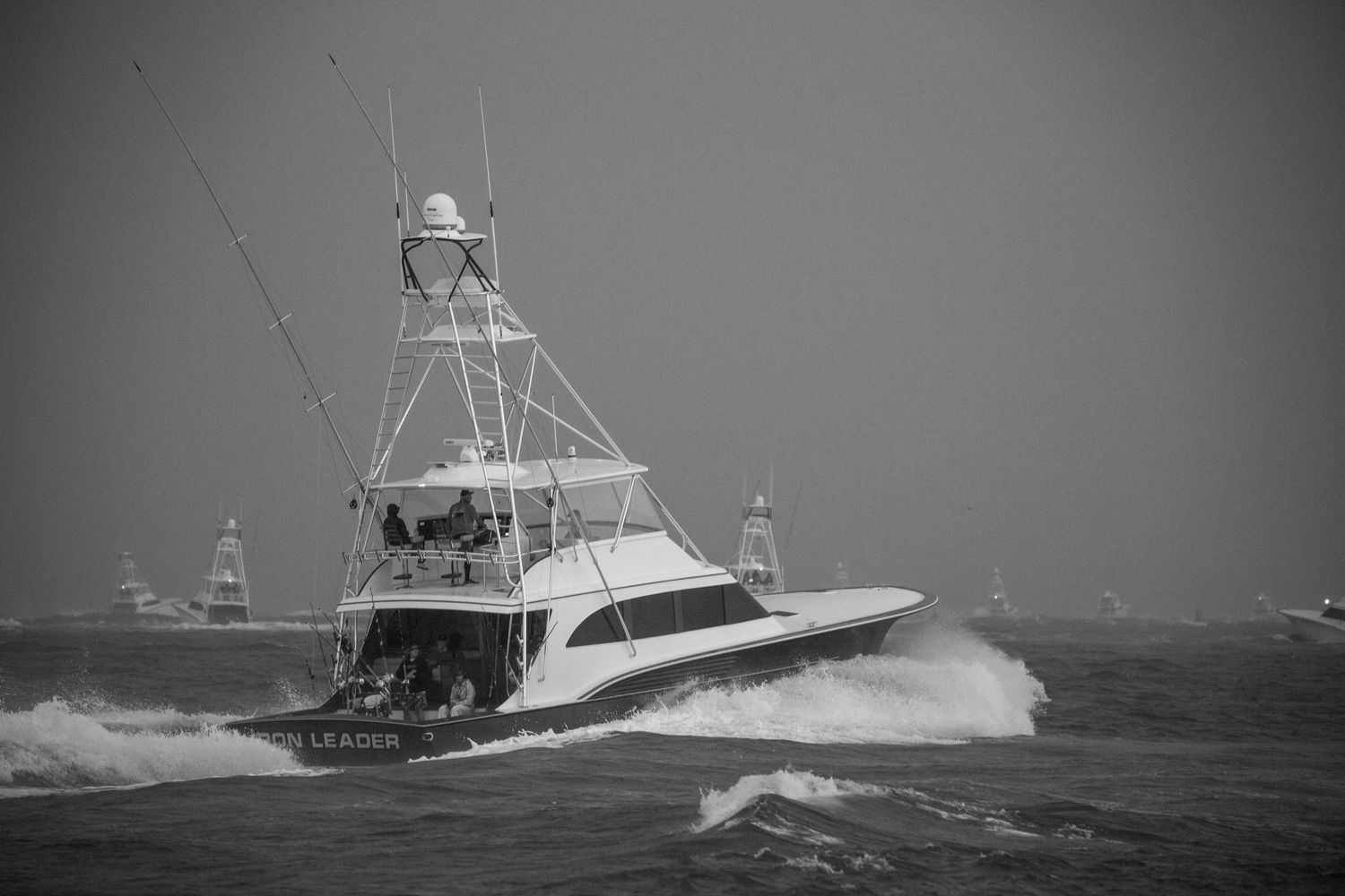 Sportfishing boats power through turbulent ocean waves in challenging weather.