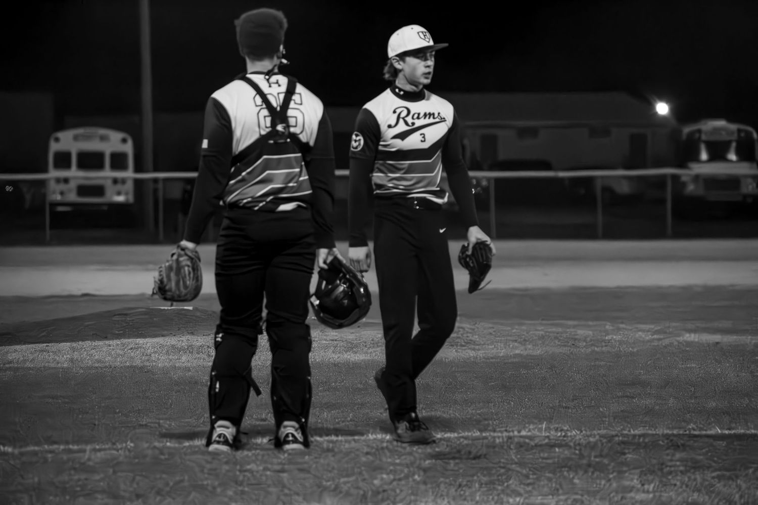 Baseball players gathered on field during game at dusk.