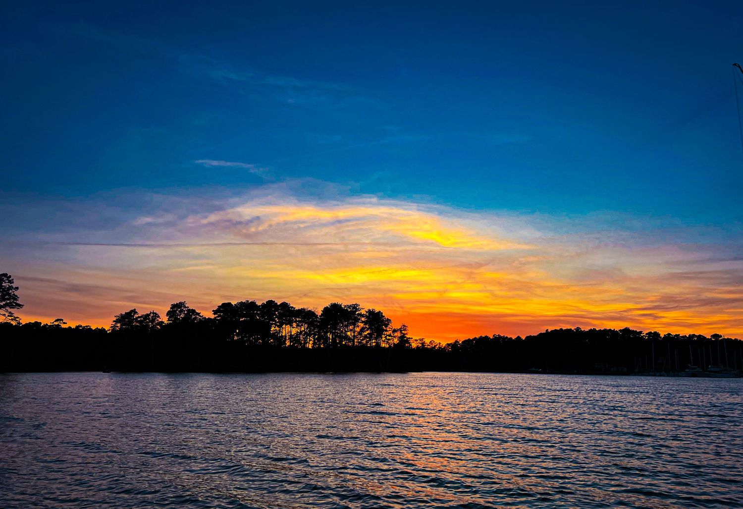 Panoramic view of lake at sunset with brilliant orange and blue sky.