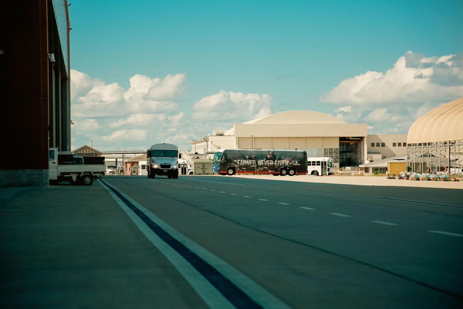 Panoramic view of an empty parking lot with buildings and a bright blue sky on a sunny day.