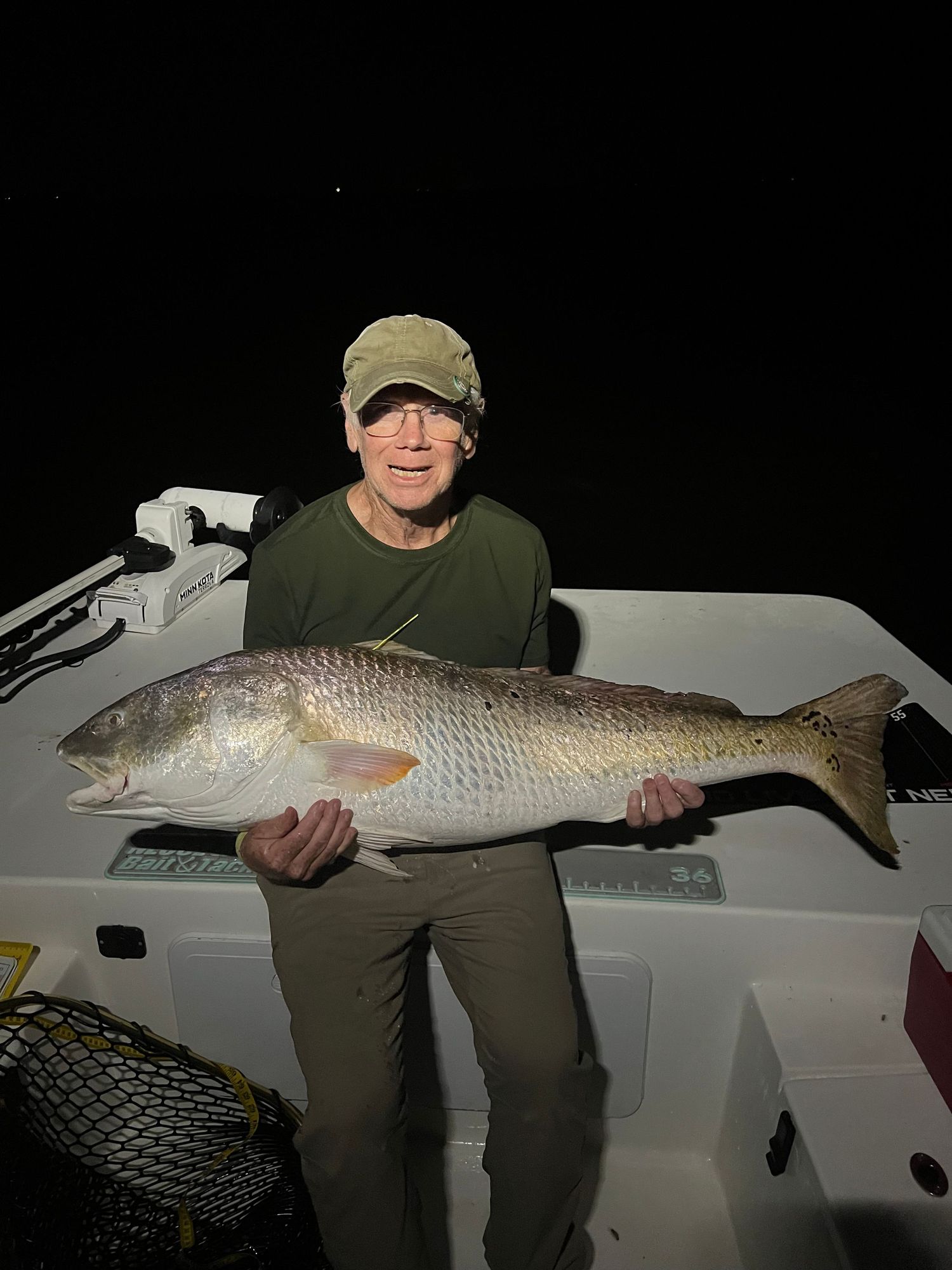 Impressive redfish catch displayed on boat deck at night.