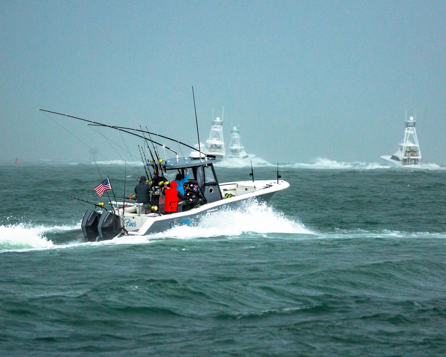 Sport fishing vessels traverse through rough waters with dramatic wave action.