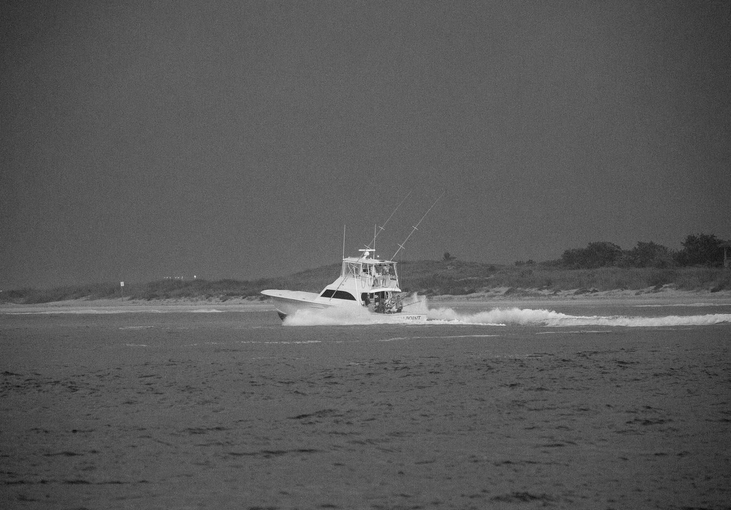 Sport fishing boat cruising across calm waters in black and white.
