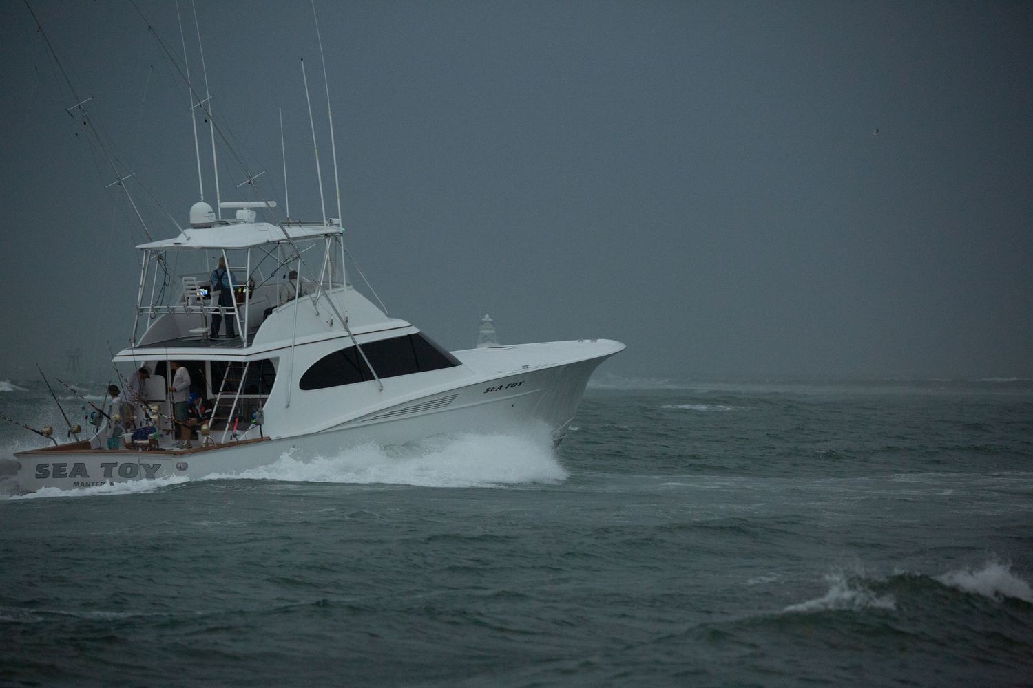 Sport fishing vessel navigating through stormy seas with waves crashing against the bow.