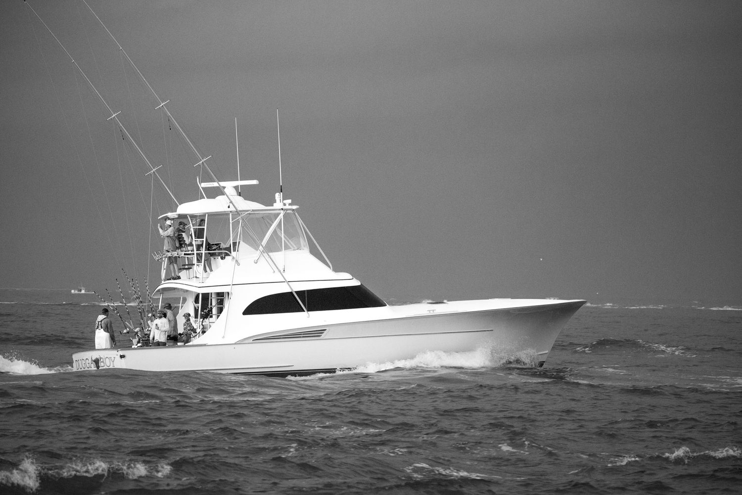 Black and white photo of a sportfishing yacht cruising through choppy ocean waters.