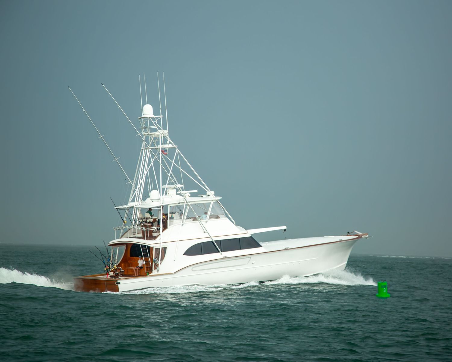 Sport fishing boats moving through blue waters with navigation markers visible.
