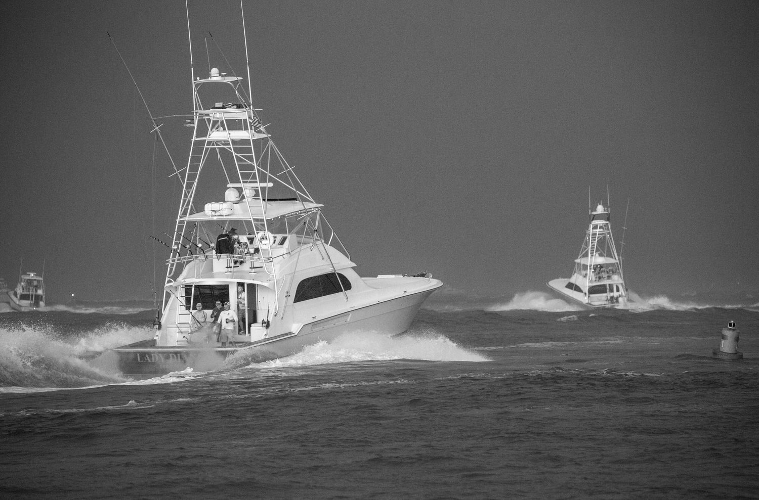 Charter fishing boats navigate through heavy seas with large waves crashing against their hulls.