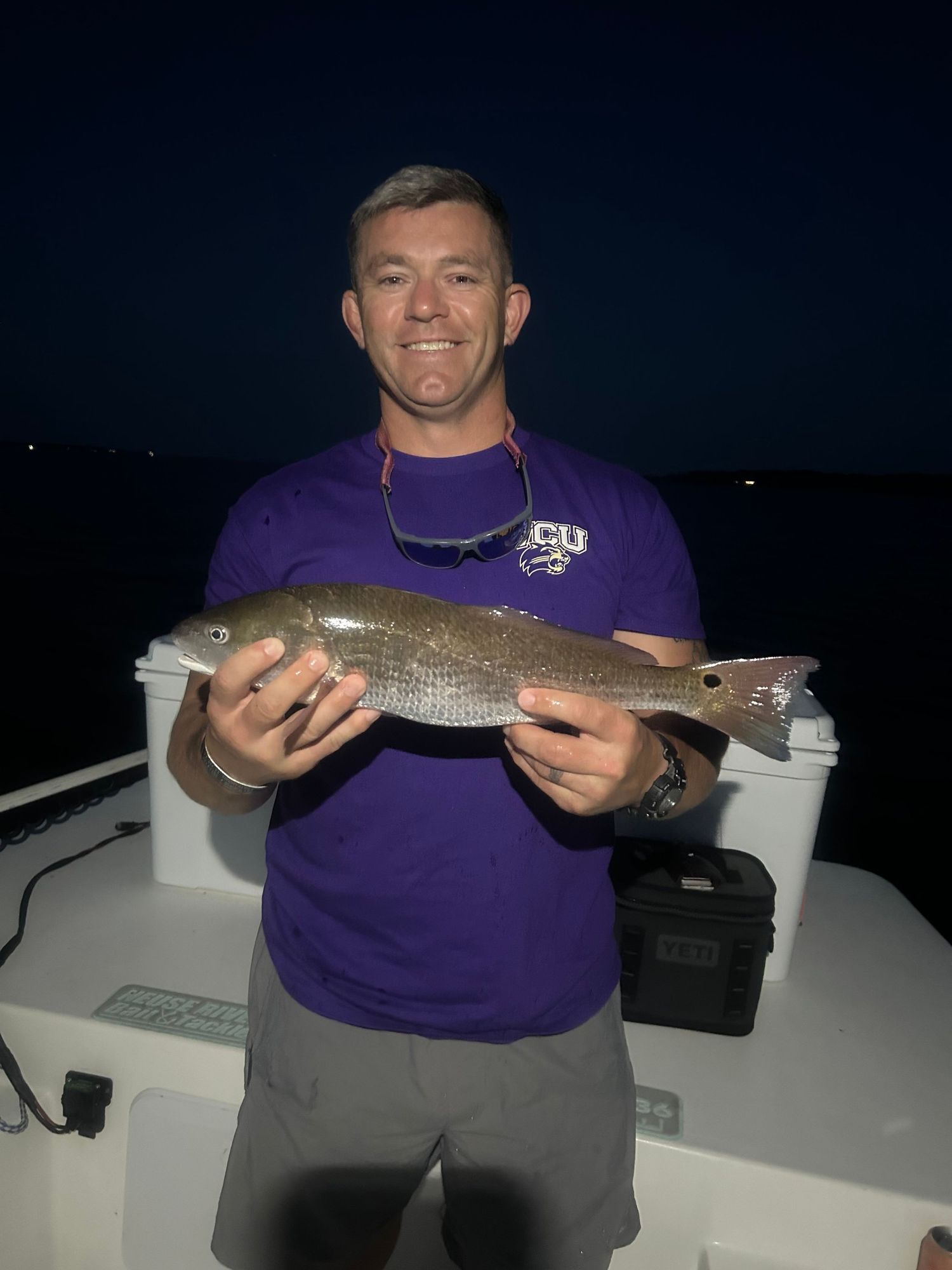 Angler displays fresh whiting catch during nighttime fishing trip.