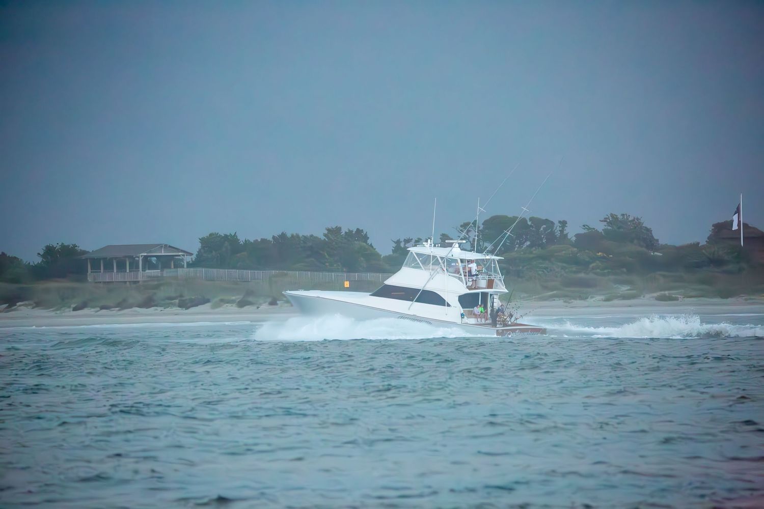 Marine vessels navigating stormy coastal waters with buildings visible on distant shore.