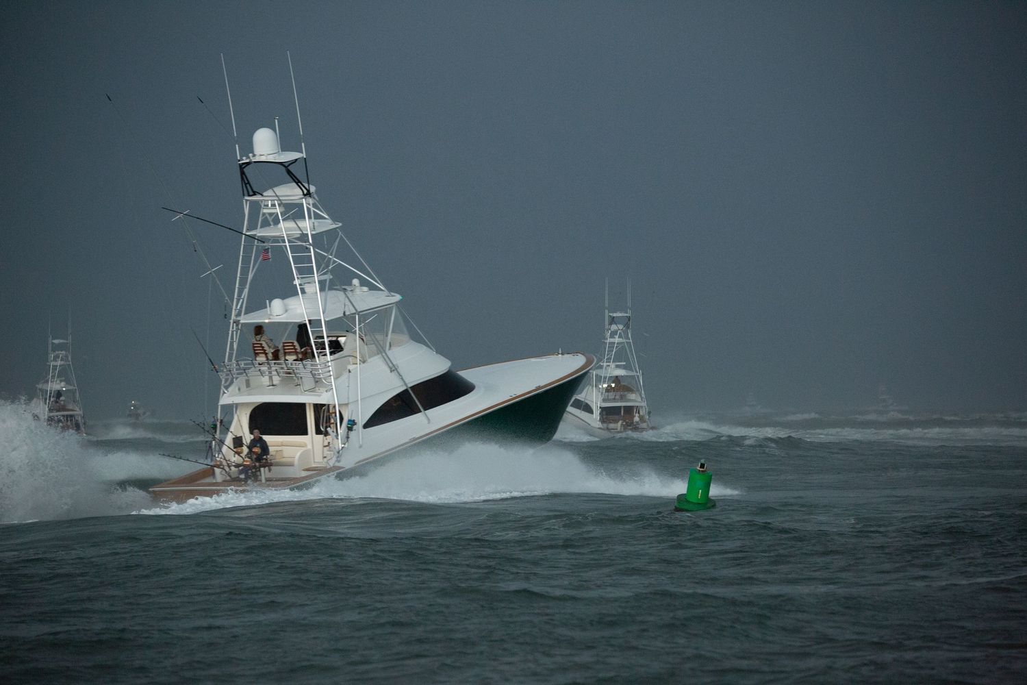 Sport fishing yacht riding a large wave in stormy weather conditions.