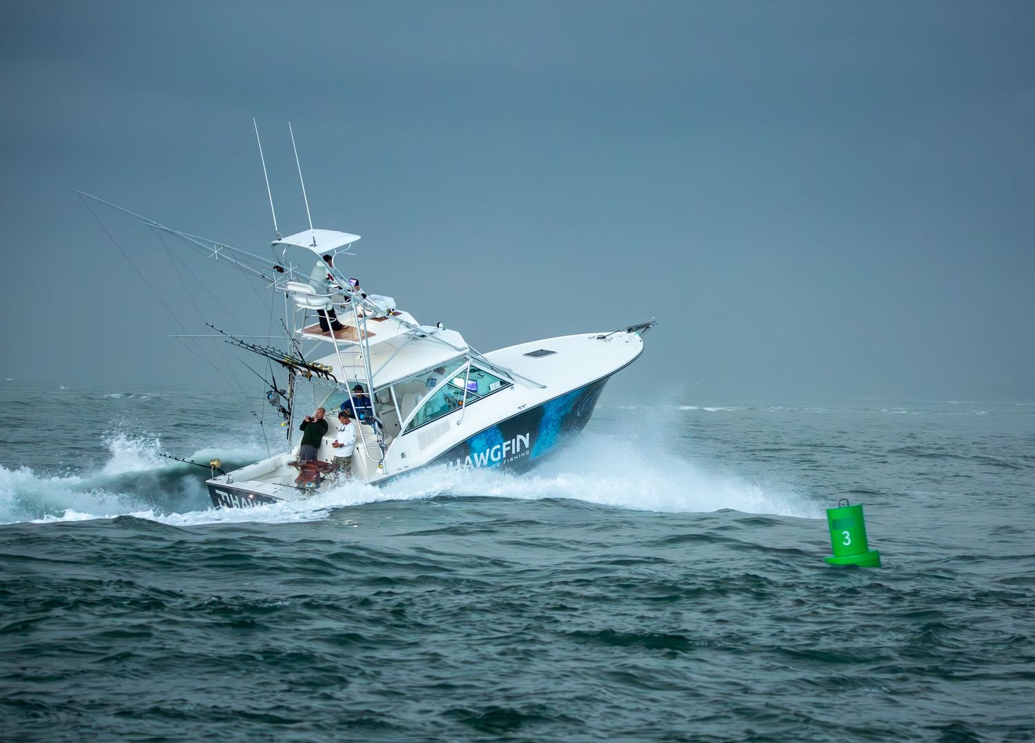 Charter fishing boat rides large swells with green navigation marker visible in background.